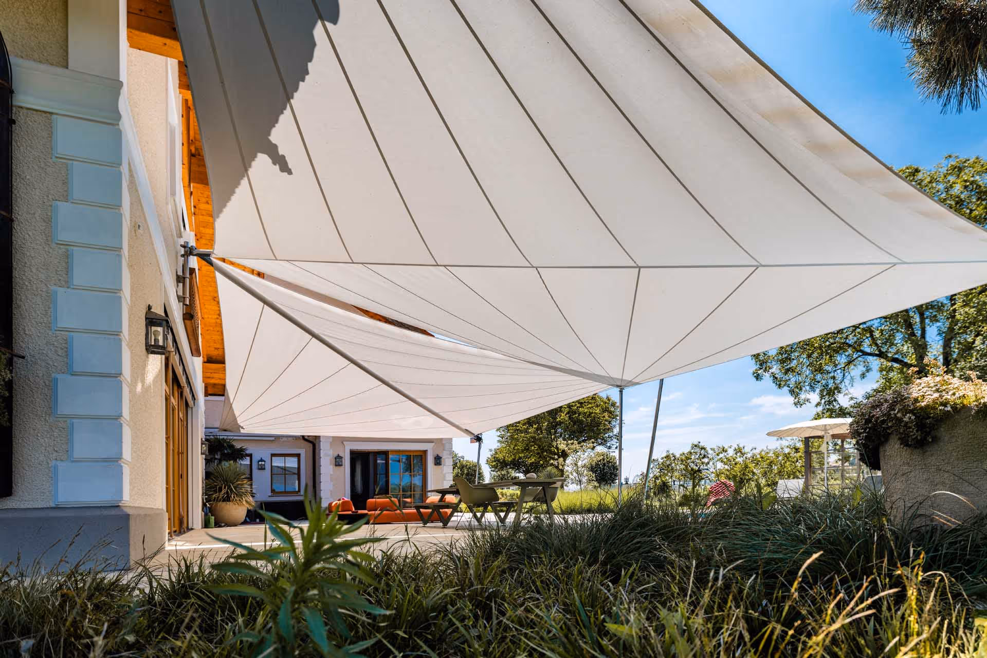 Elegante Sonnensegel in dezentem Farbton harmonieren mit der hochwertigen Outdoor-Ausstattung.
