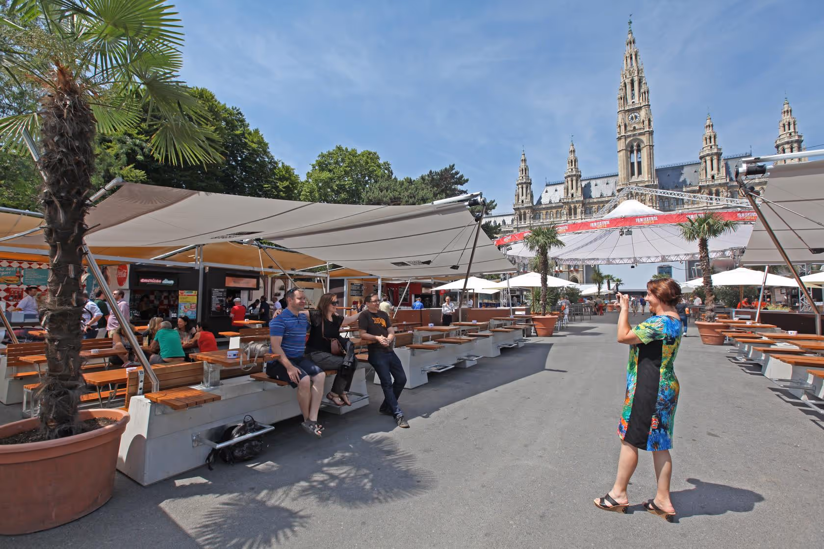 Outdoor-Gastronomiebereich beim Wiener Rathausplatz mit SunSquare-Beschattung, Gäste unter Sonnensegeln und historischer Kulisse im Hintergrund.