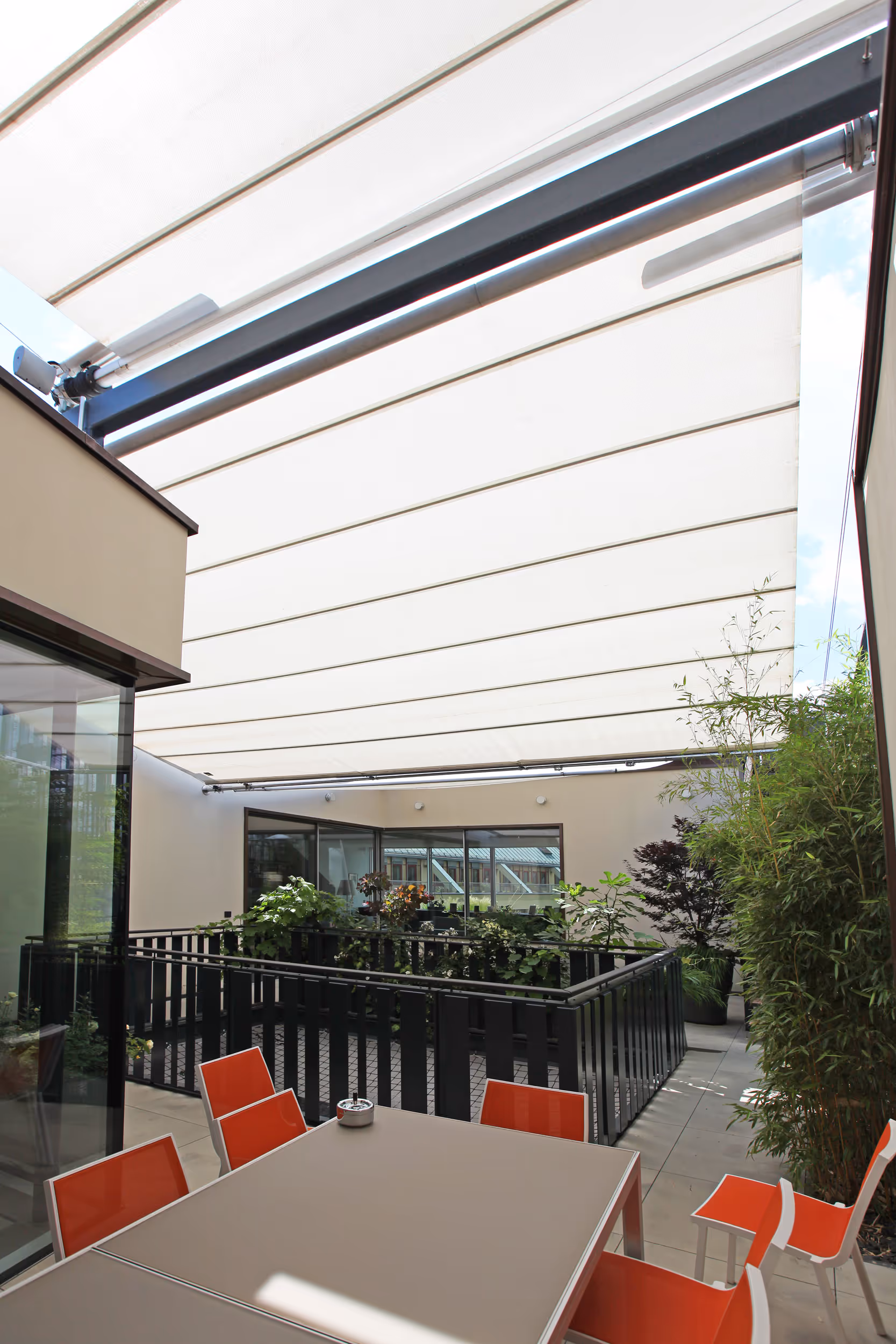 Dreifach ausgeführte SunSquare Sonnensegelanlage bietet präzisen Sonnen- und Regenschutz im Atrium.