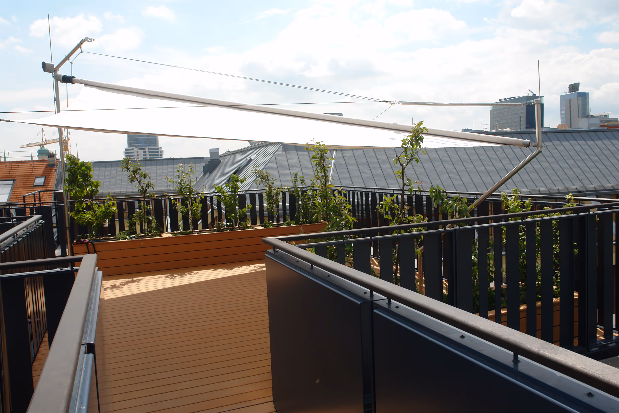 Maßgeschneiderte SunSquare Sonnensegelanlage bietet stilvollen Sonnen- und Regenschutz auf exklusiver Dachterrasse.