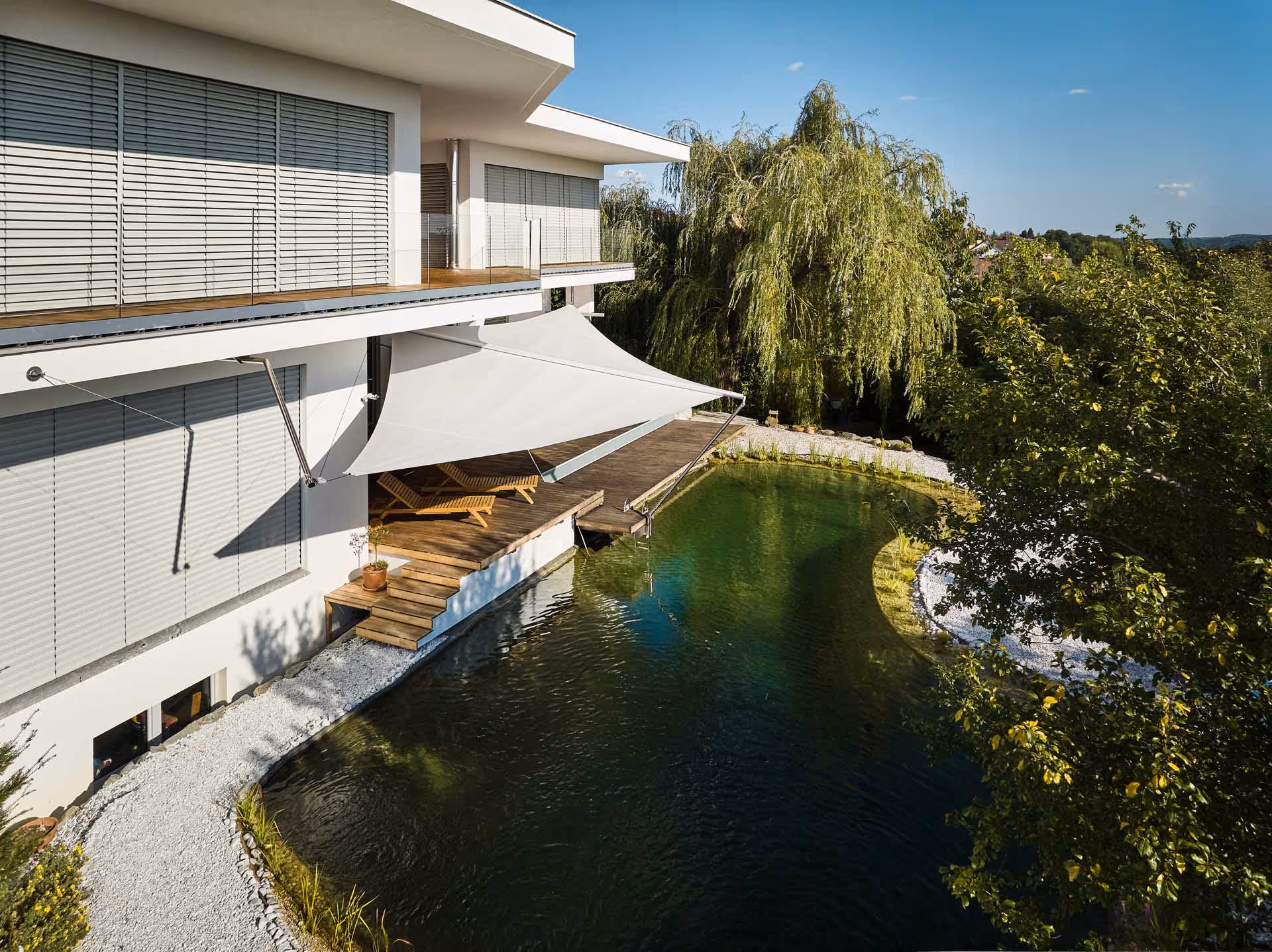 Wie zwei Elemente einer Komposition verbinden sich Schwimmteich und Holzdeck zu einem stimmigen Ensemble, das Ruhe, Ästhetik und Funktion miteinander vereint.