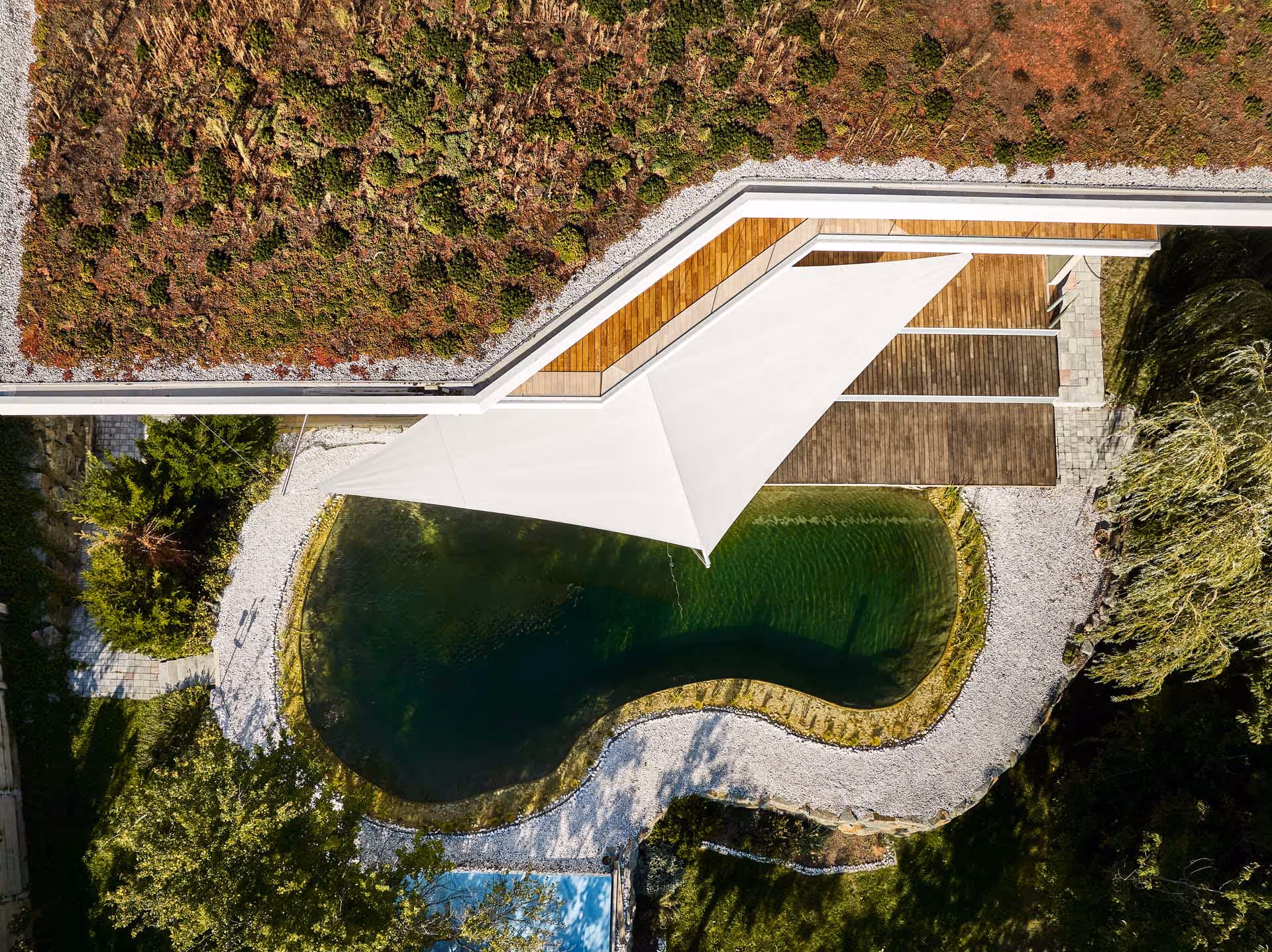 Luftaufnahme: Maßgeschneiderte Lösung für zweistufiges Holzdeck mit angrenzendem Schwimmteich.