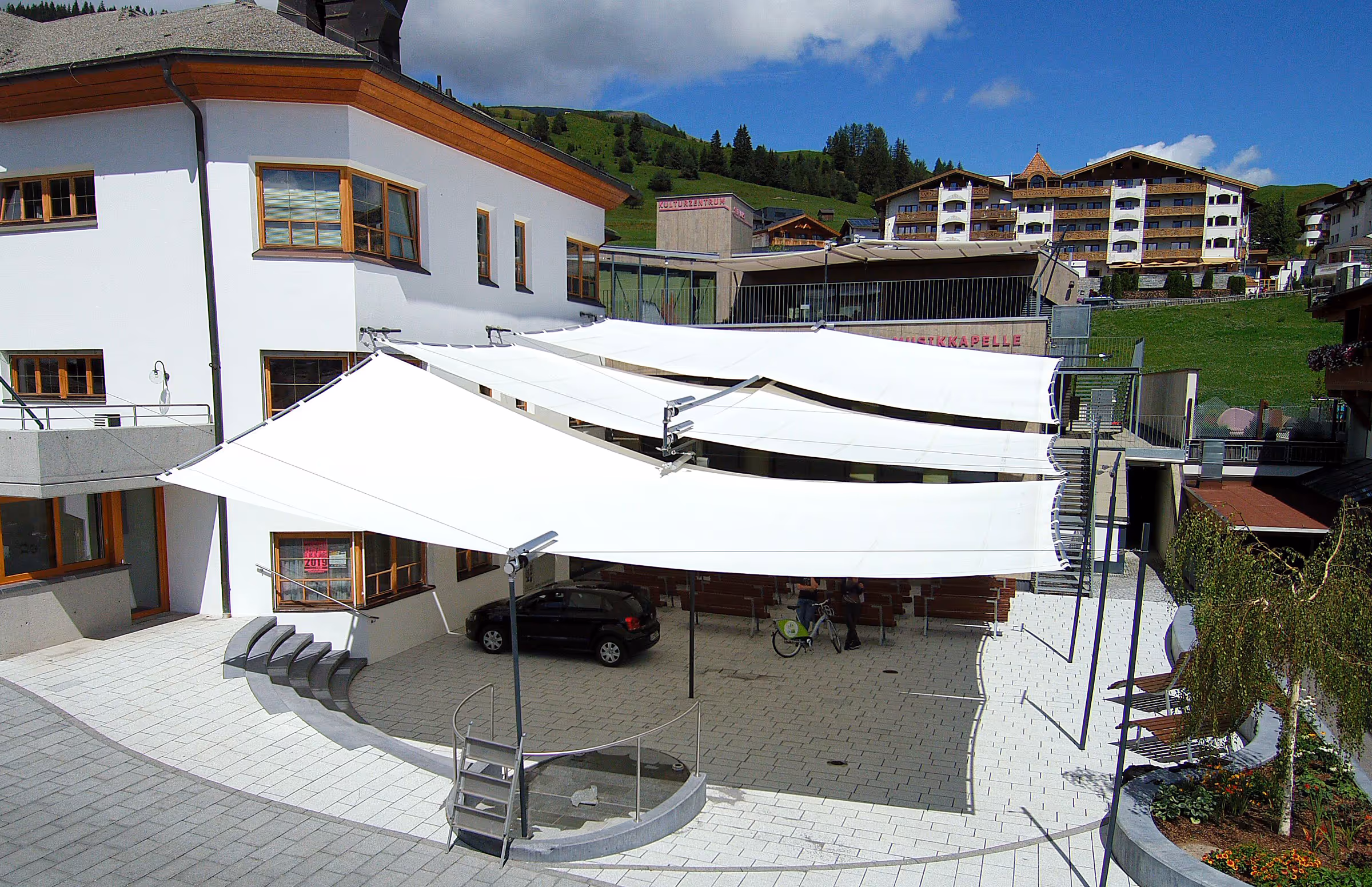 Luftaufnahme zeigt die gestalterische Symmetrie und die Integration in die alpine Umgebung.