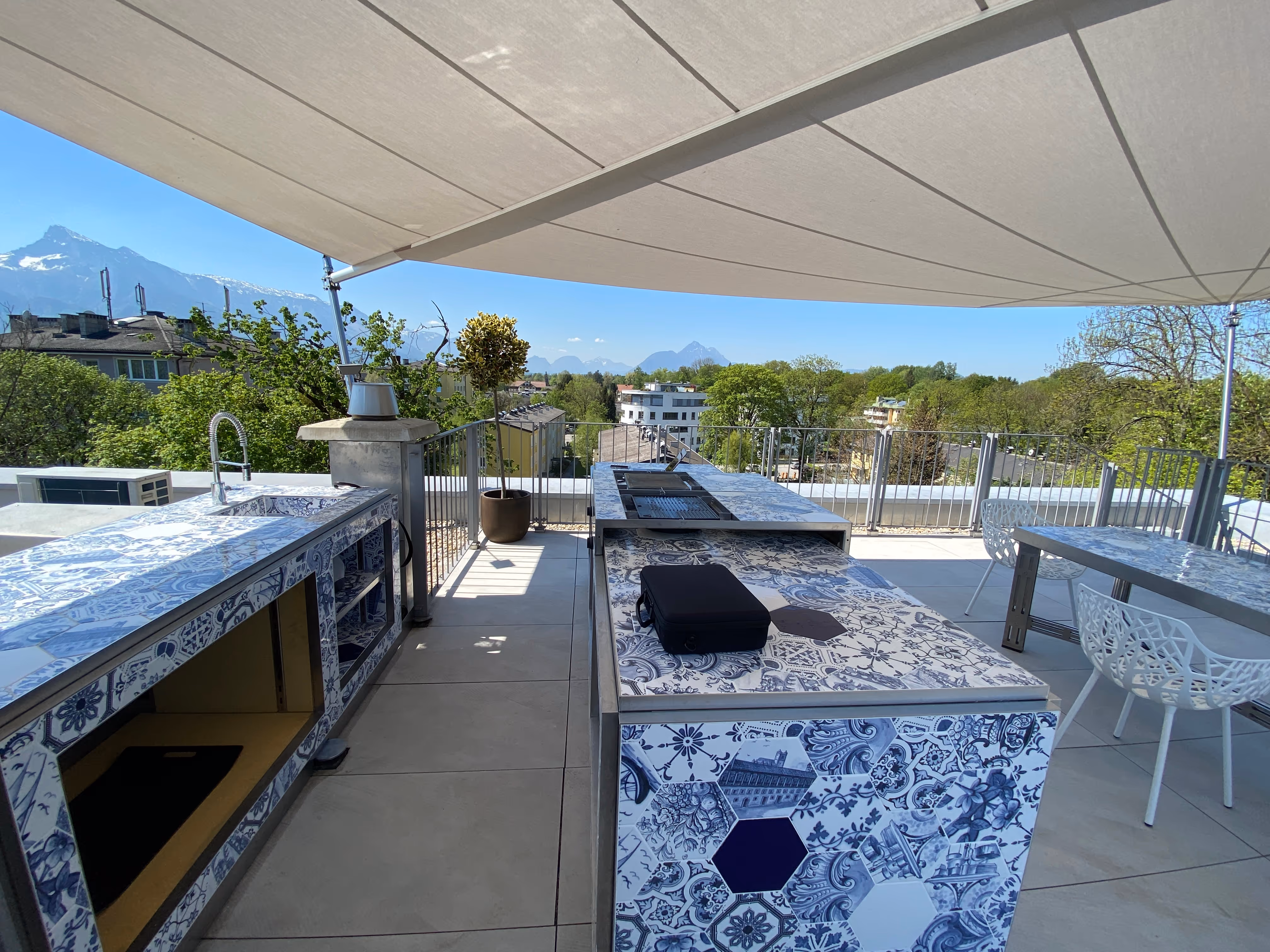 Unter einem SunSquare Sonnensegel befindet sich eine Outdoor Küche und der Essbereich.