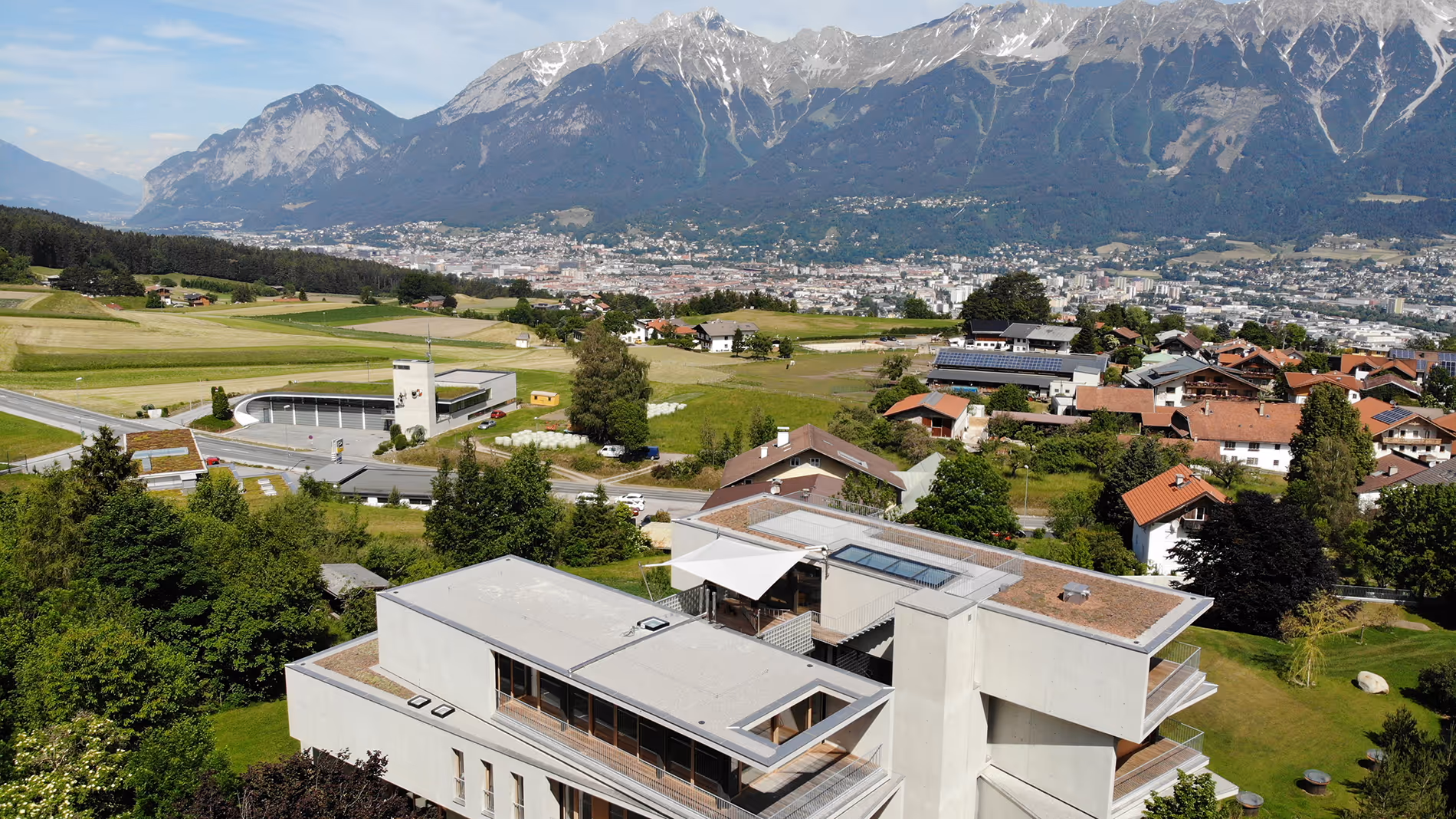 Luftaufnahme der SunSquare Strahlensegelanlage auf einer Dachterrasse mit beeindruckendem Bergpanorama.