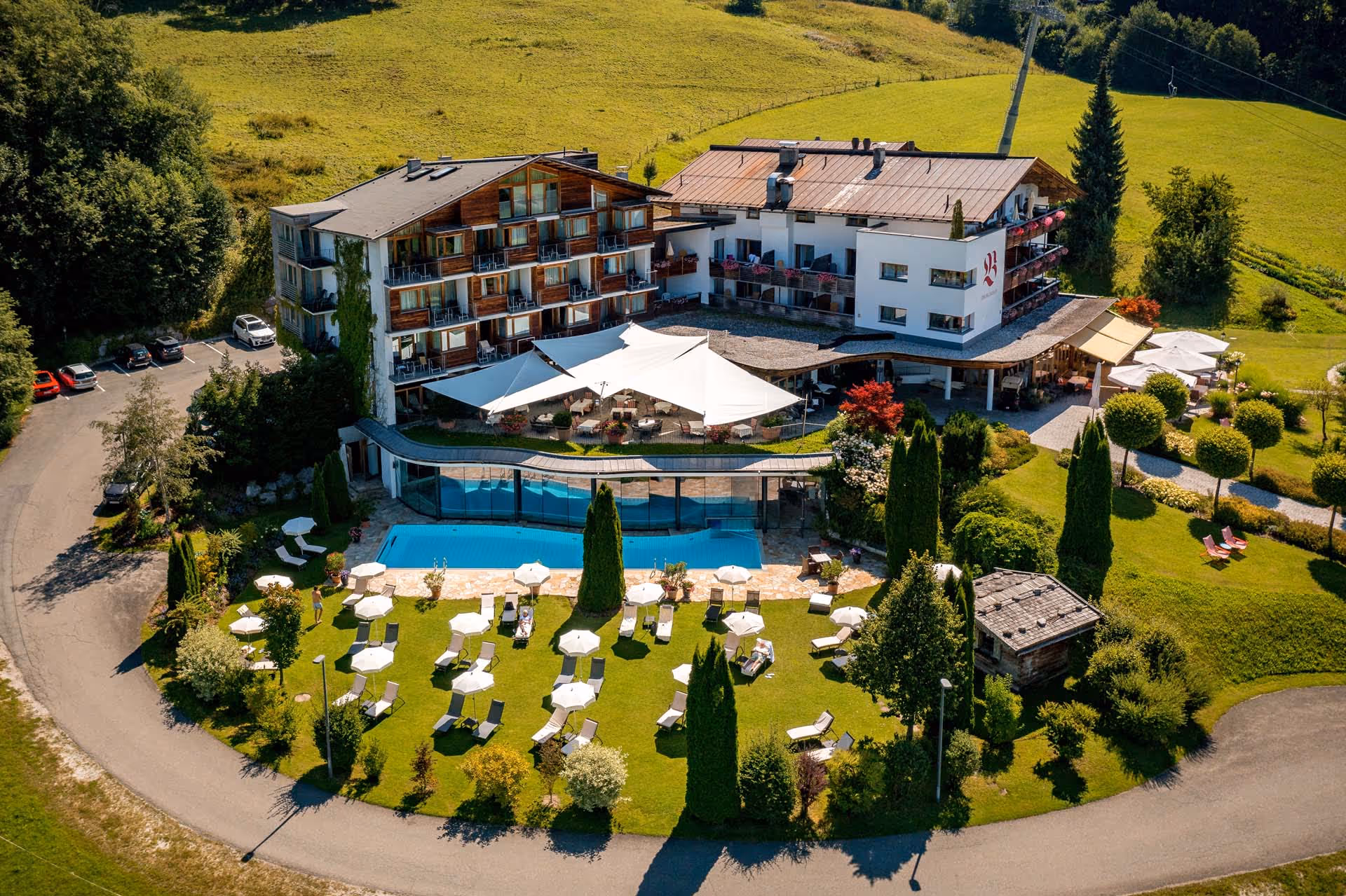 Luftaufnahme der SunSquare Strahlensegelanlage am Bichlhof mit Blick auf die Kitzbüheler Alpen.