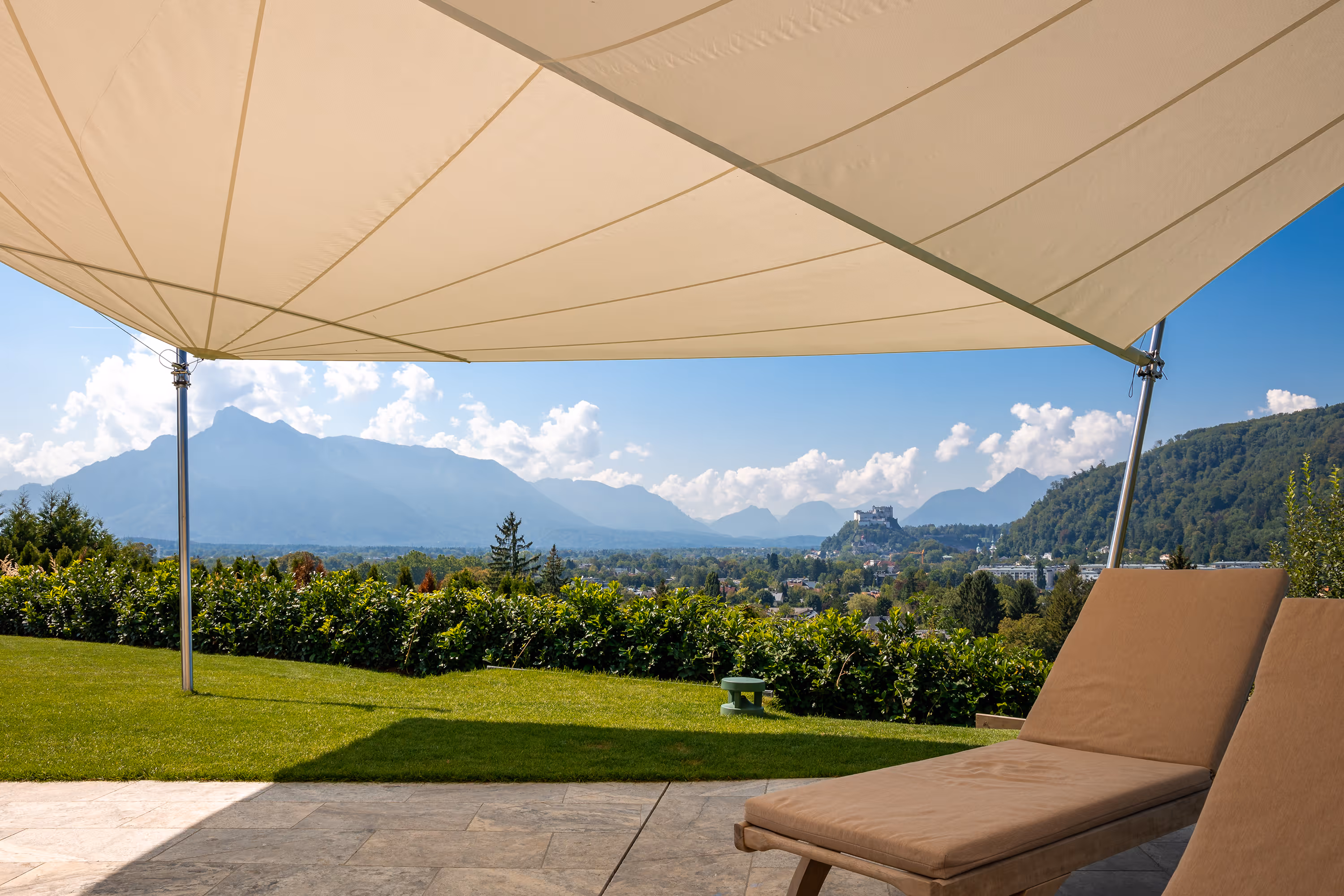 Zwei Sonnenliegen im SunSquare Schatten, die Festung Salzburg im Hintergrund.