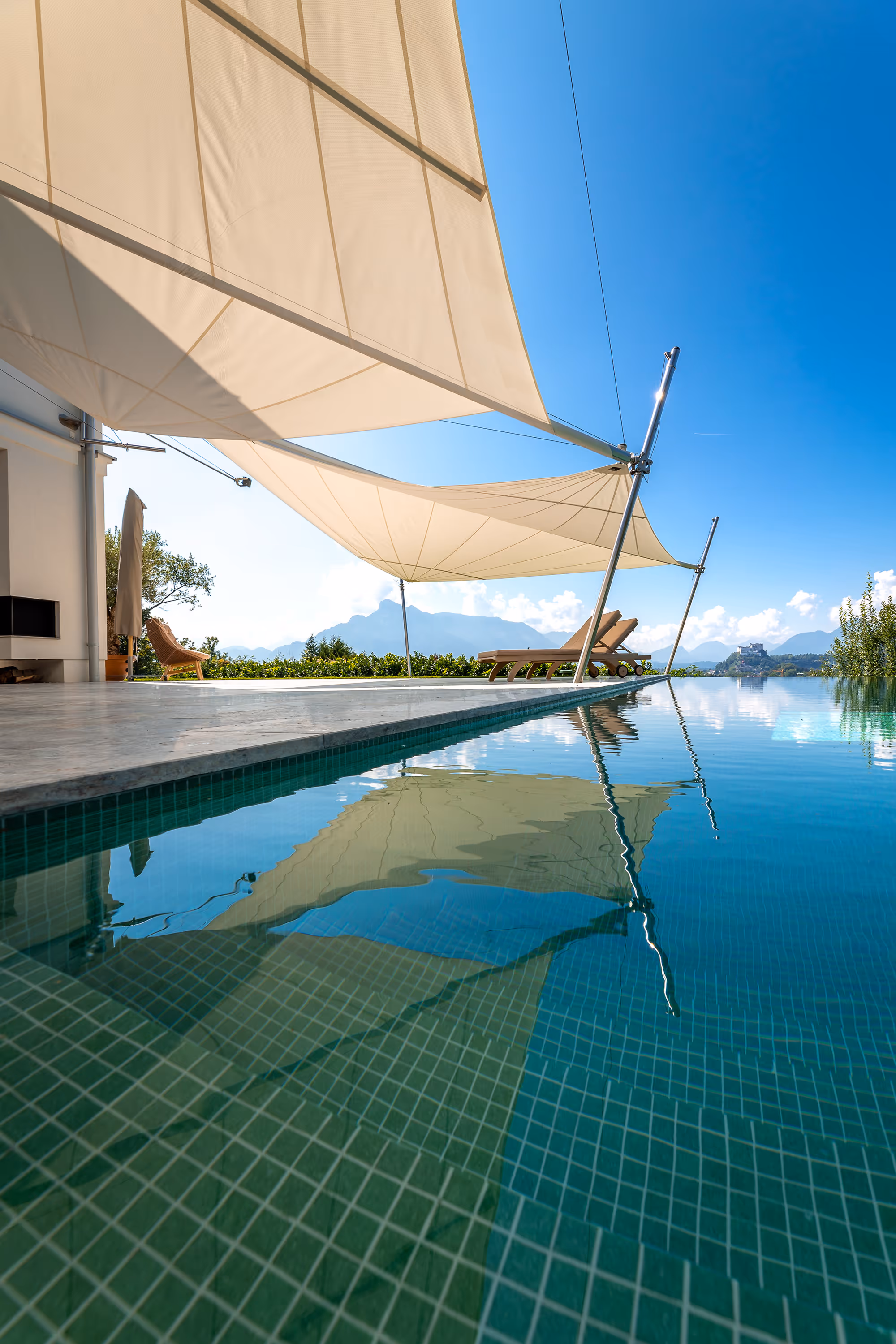 Wunderschöne Kulisse - türkis-grünes Poolwasser, die SunSquare Sonnensegel werfen beschützend ihren Schatten.