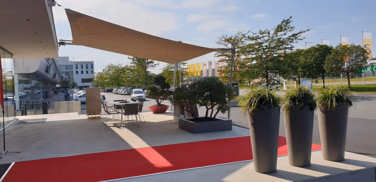 SunSquare Strahlensegel mit 36 m² Fläche schafft eine stilvolle, wetterfeste Erweiterung des Schauraums.
