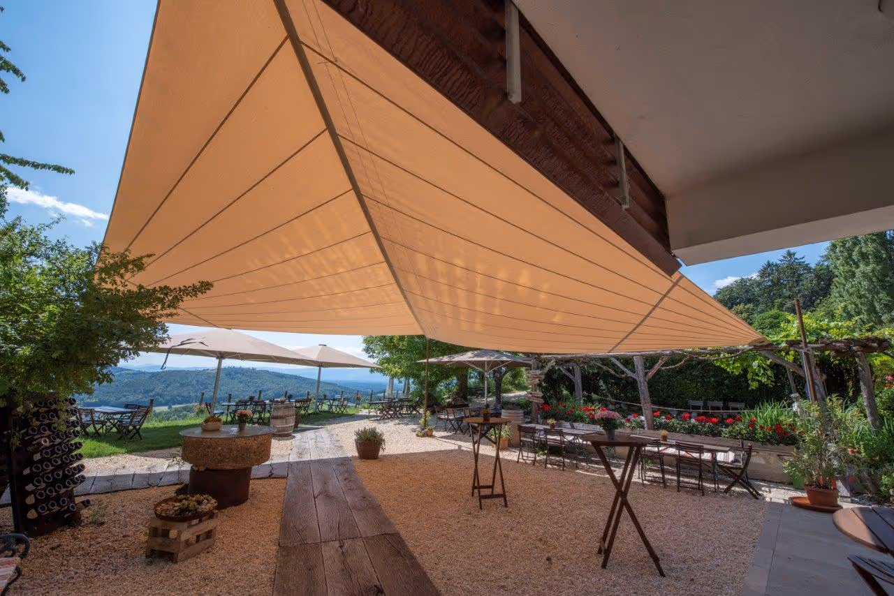 Designstarke Beschattungslösung mit stufenloser Höhenverstellung – windstabil, komfortabel und perfekt abgestimmt auf die exklusive Architektur des Weingartenhotels.