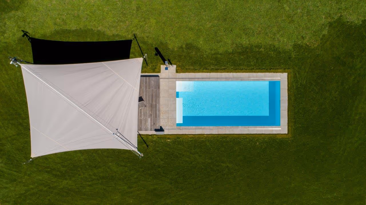 Freistehende Sonnensegelanlage auf vier Bodenstützen zum Schutz des Pool-Bereichs.
