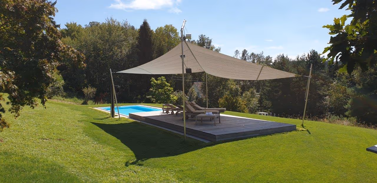 Freistehende Sonnensegelanlage auf vier Bodenstützen zum Schutz des Pool-Bereichs.