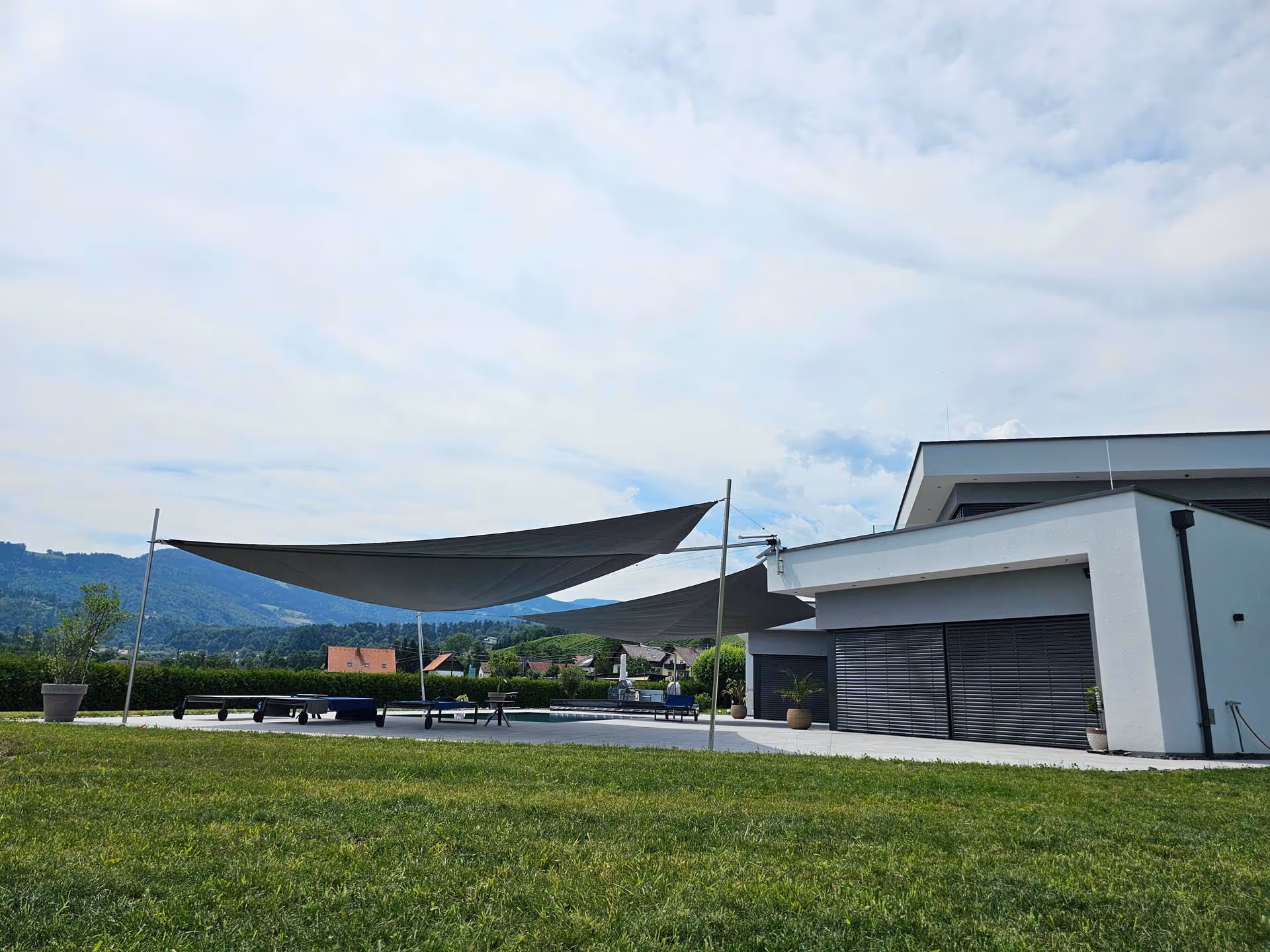 Beschattung der Glasfassade durch textile Segel – spürbare Reduktion der Wärmeentwicklung im Innenraum.