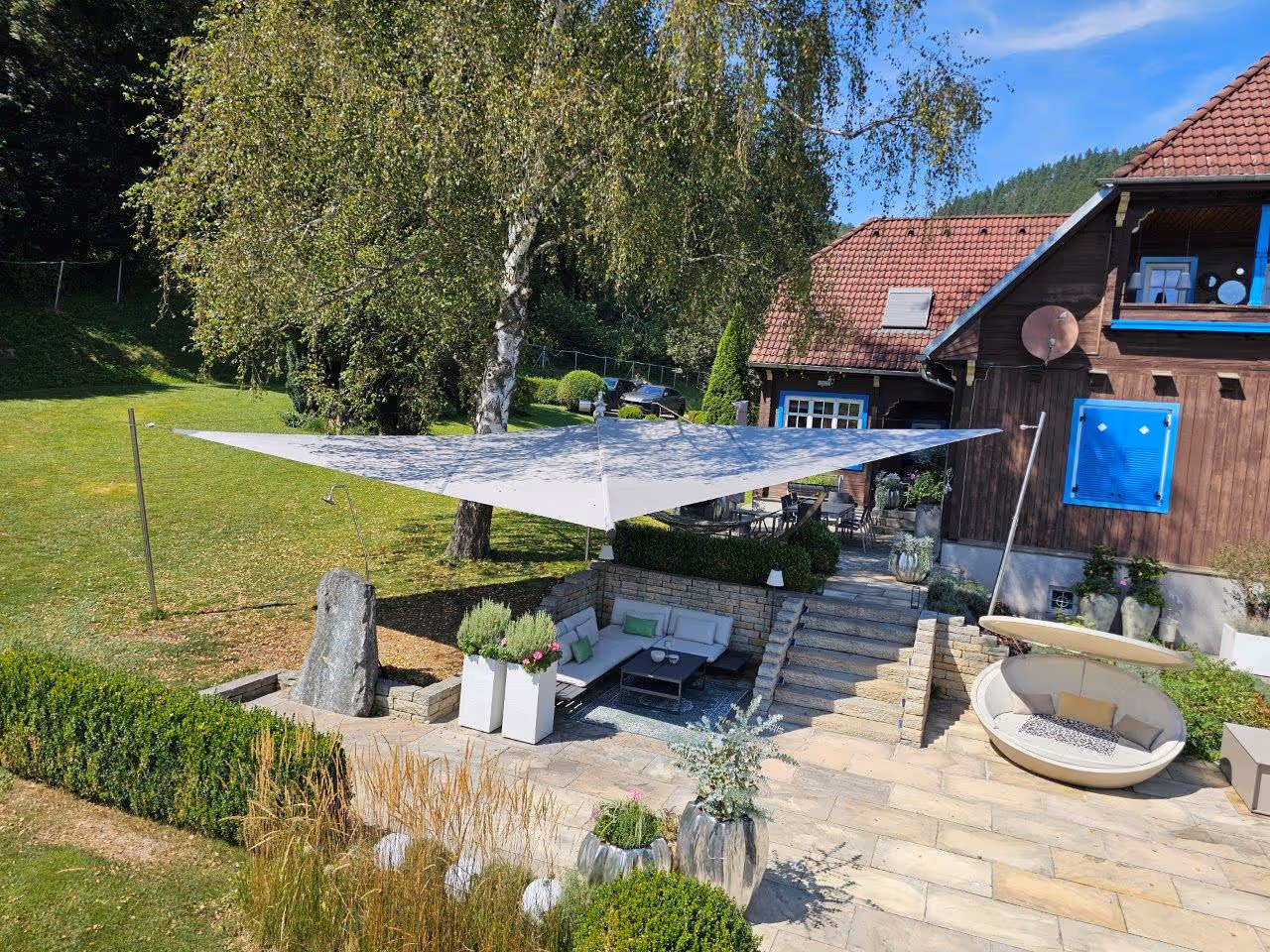 Luftaufnahme des Gartens mit Pool, überdachter Terrasse und SunSquare Cantilever Sonnensegel inmitten einer grünen Gartenlandschaft.