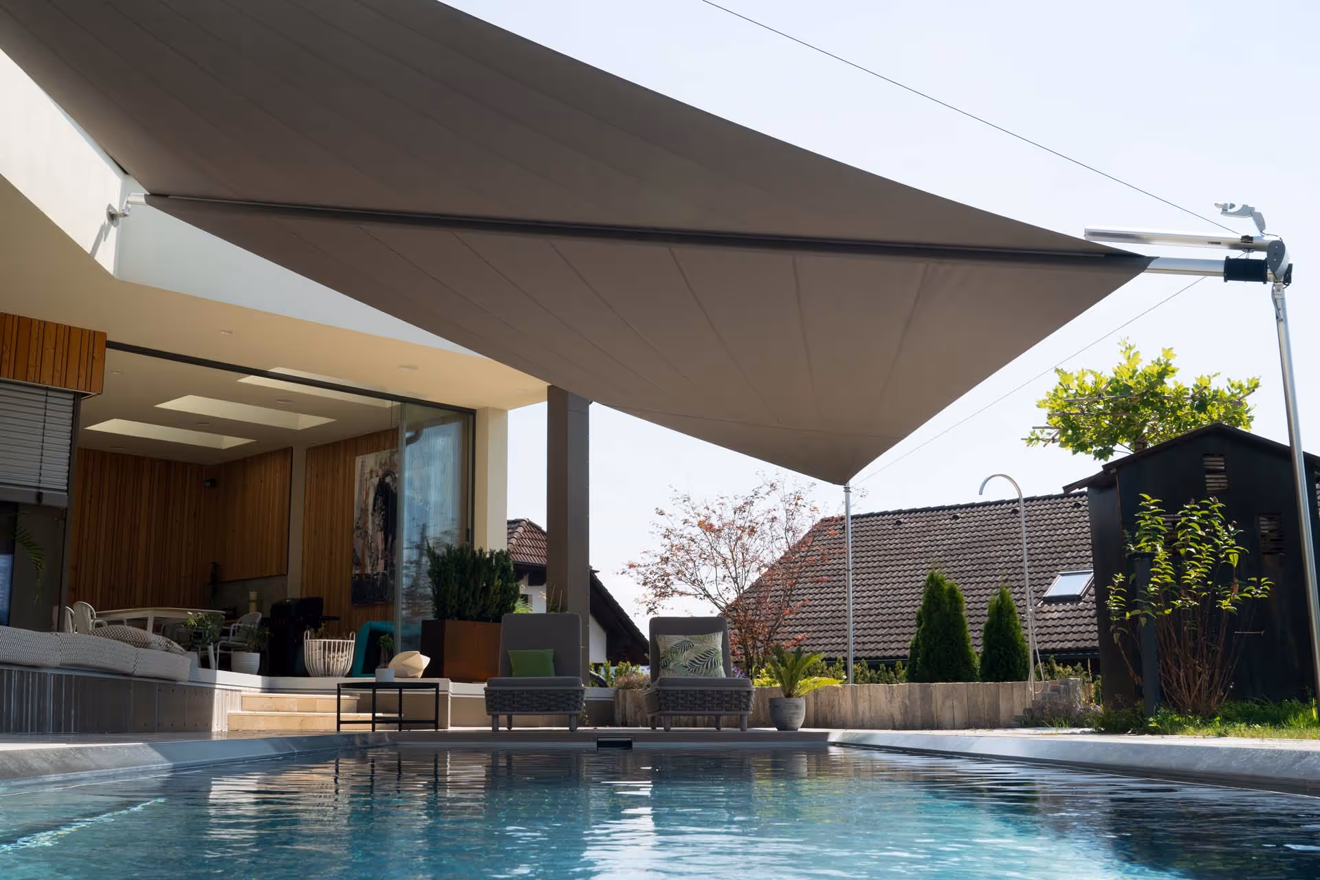 SunSquare shade sail provides stylish shade and rain protection over the pool and sunbathing area of a modern single-family home.