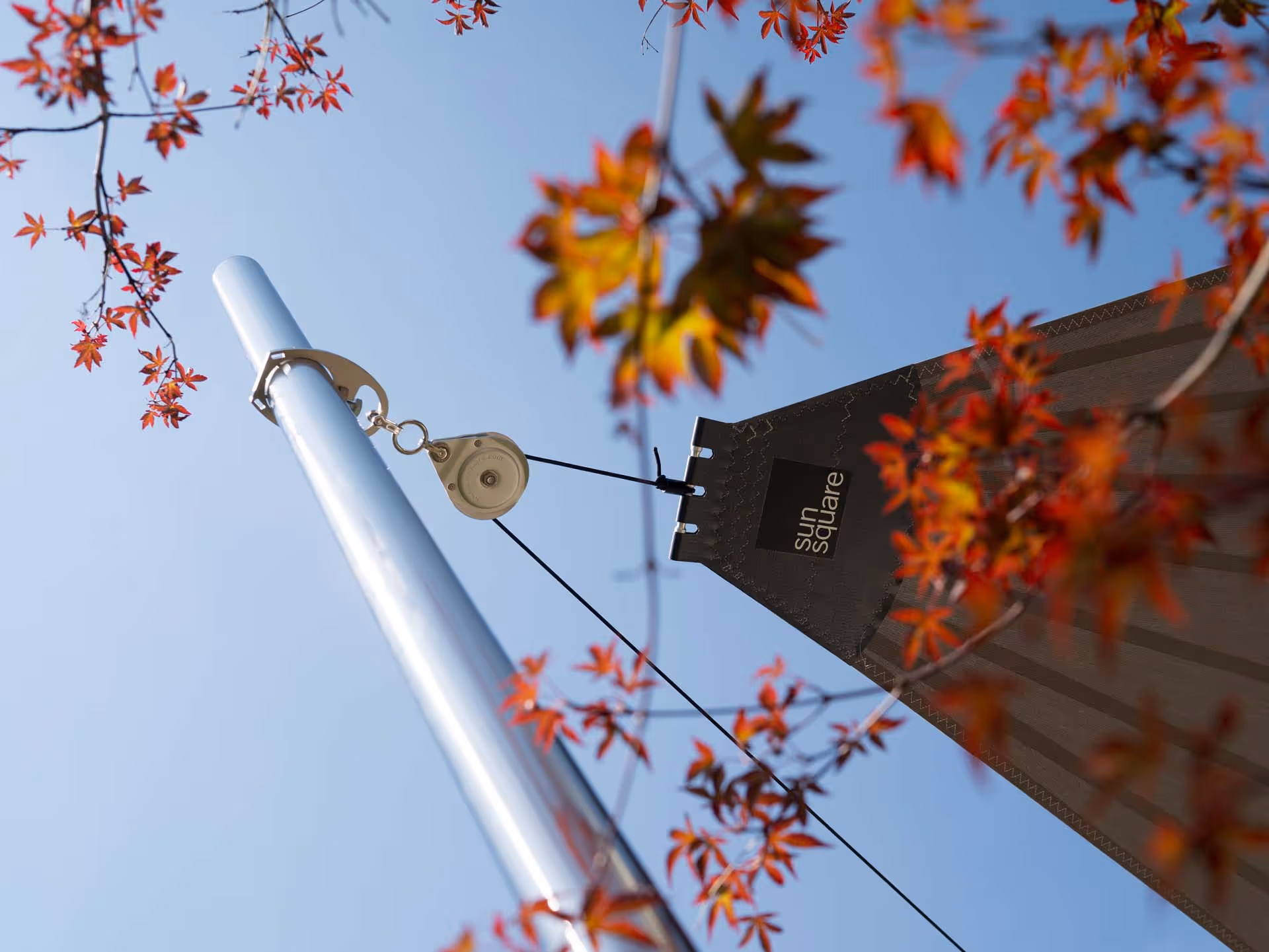 Ein Segelende von SunSquare mit einer SunSquare Stütze umringt von herbstlich anmutenden Pflanzen.
