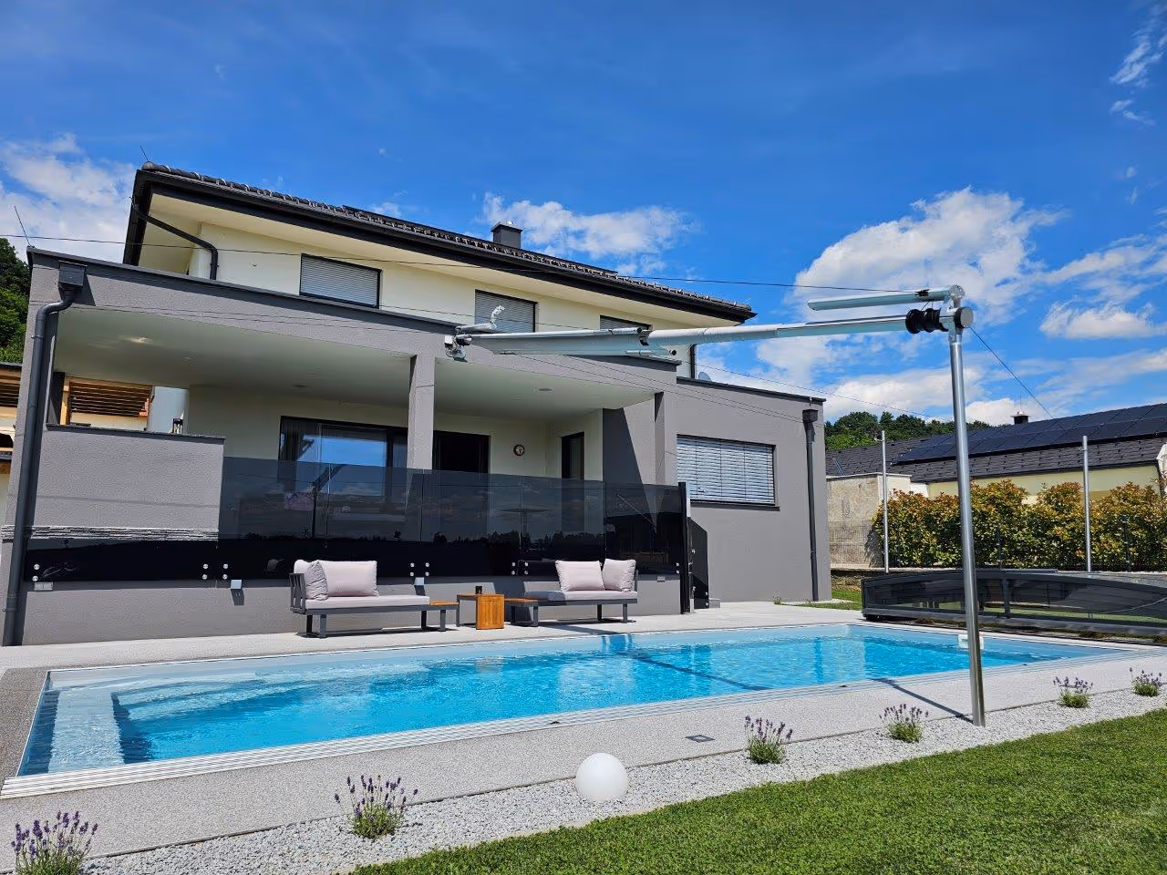 Die Tuchwelle wurde mittig über den Pool ausgerichtet - auf der Hausseite an der Fassade montiert und an der gegenüberliegenden Seite mittels Bodenstütze befestigt.