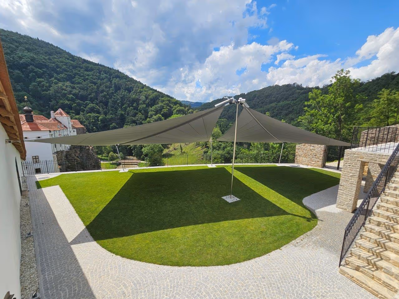 Beschattete Veranstaltungsfläche im Schlossgarten Herberstein mit weißen Stühlen unter SunSquare-Sonnensegeln – ideal für Events im Freien.