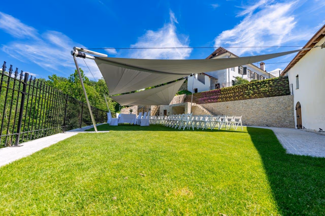 Two large SunSquare sails in the garden of Herberstein Castle, with a view of the historic building and the surrounding hills.