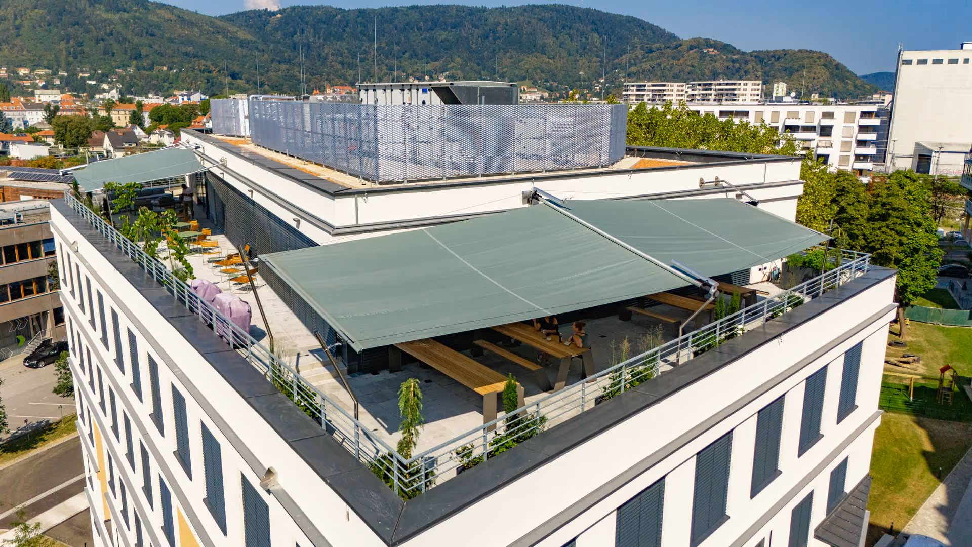 You can see an office building with a roof terrace on which two SunSquare rectangular systems have been installed on both sides. Made from Sattler 314-868 acrylic fabric in a modern zigzag sail. A project by Konrad Sonnensegel.