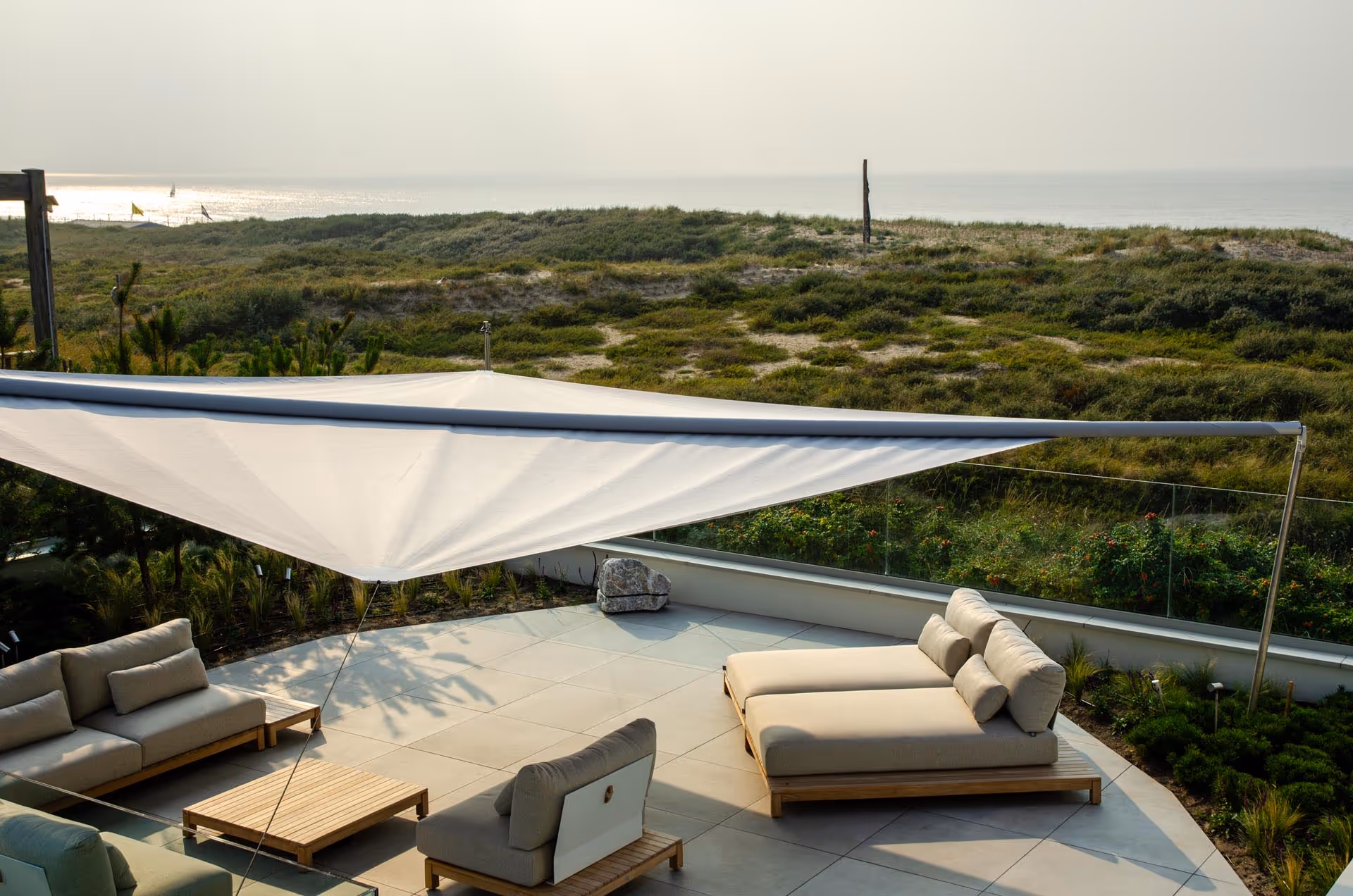 Das Segel von oben betrachtet, darunter schöne Outdoor Möbel und Liegen.