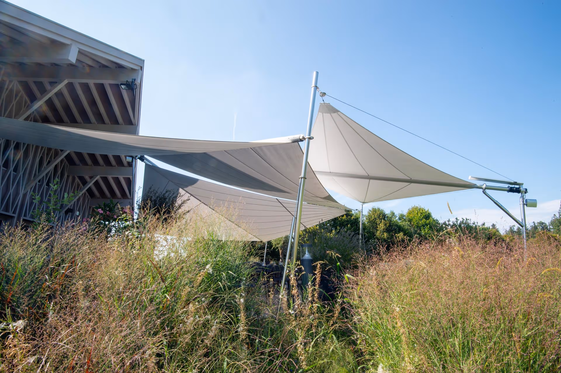 Drei SunSquare-Segel mit 140 m² Gesamtfläche auf der Golfrestaurant-Terrasse – elegante Beschattungslösung mit minimaler Stützenanzahl.