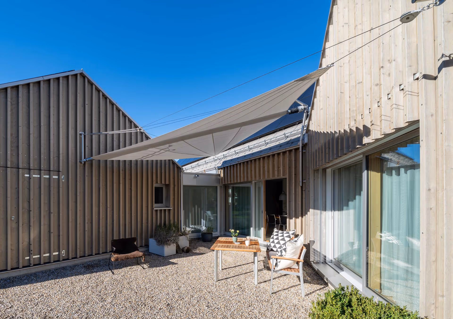 Beschatteter Sitzbereich mit Blick auf die Glasfront – zusätzlicher Wohnkomfort durch reduzierte Wärmeentwicklung im Innenraum.