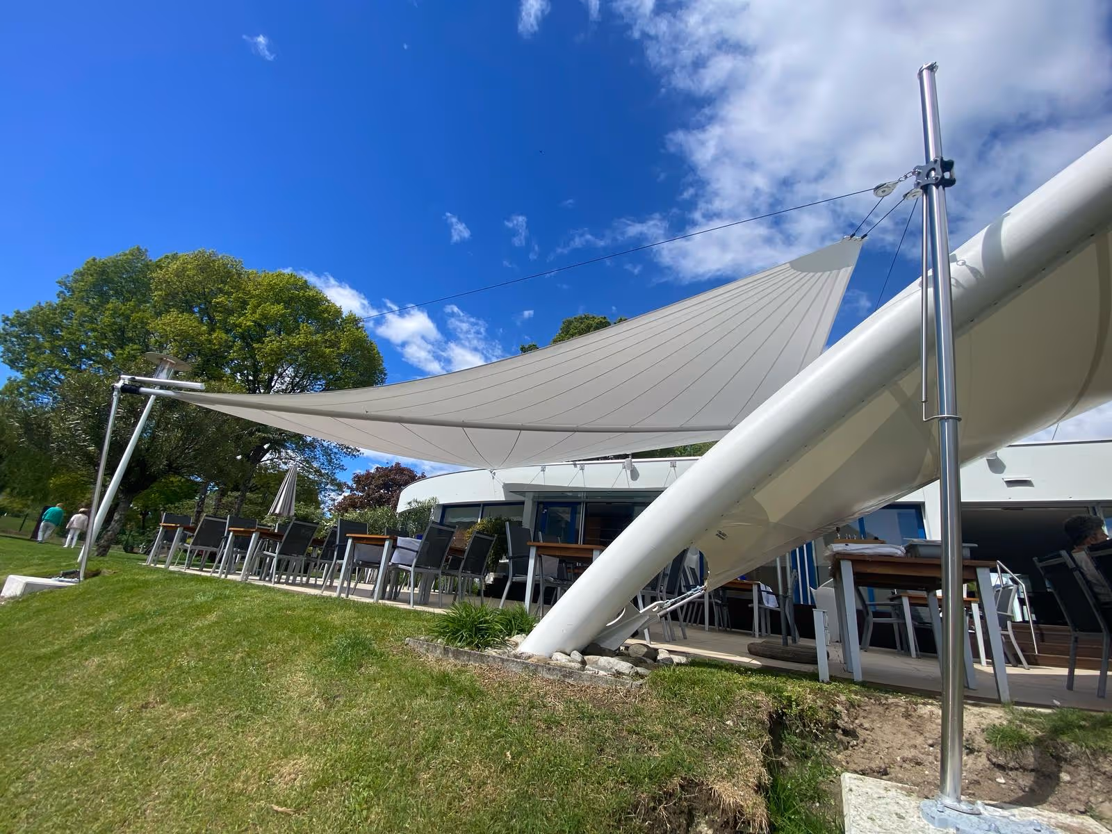 Blick auf die Gastronomie-Terrasse mit SunSquare-Segeln und Fixverspannung – stilvoller Sonnen- und Regenschutz mit Blick auf den Lago Maggiore.
