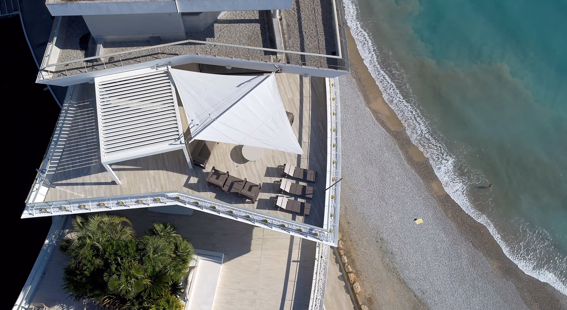 Luftaufnahme des SunSquare Segels. Man sieht das Meer und das Gebäude.