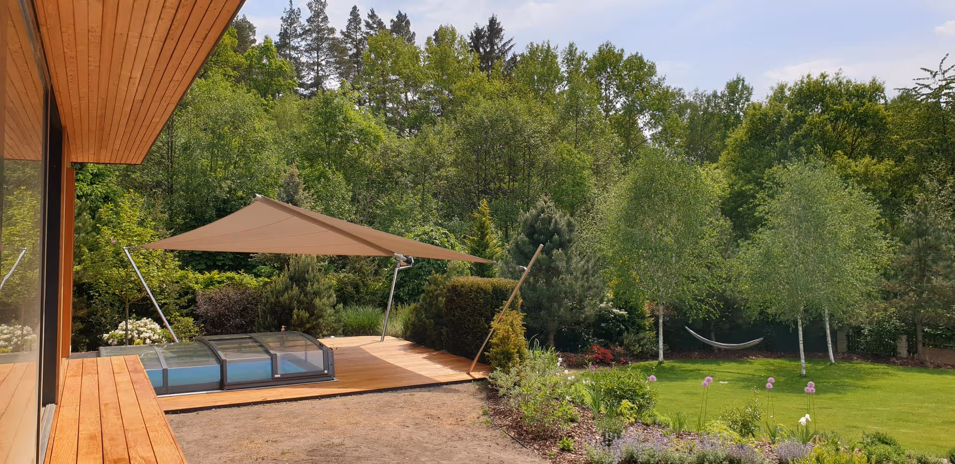 Ein Garten angelegt auf zwei Ebenen - sattes Grün und ein Pool auf einer Anhöhe laden zum Verweilen ein.