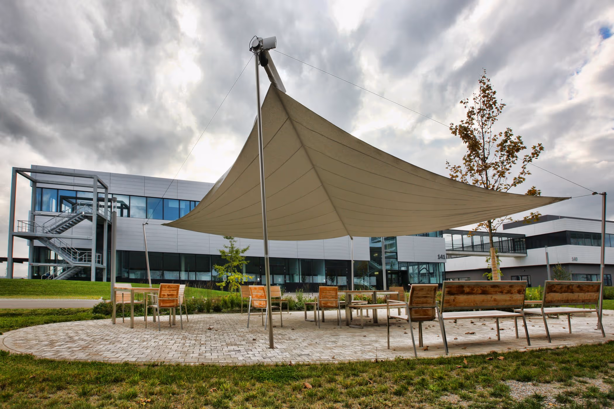 Eine freistehende SunSquare Anlage, die einen Sitzbereich im Freien vor Sonne und Regen schützt.