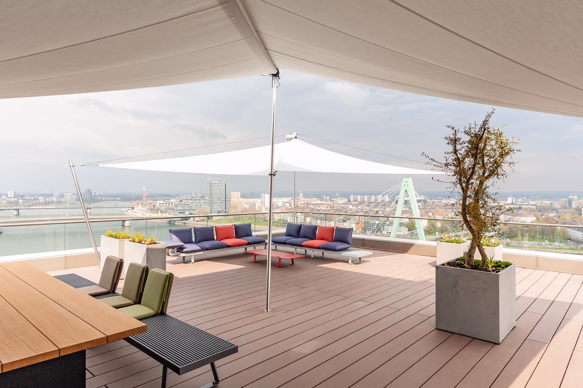 Ansprechend inszenierte und ausgestattete Dachterrasse am Kranhaus Köln mit Sonnensegel.