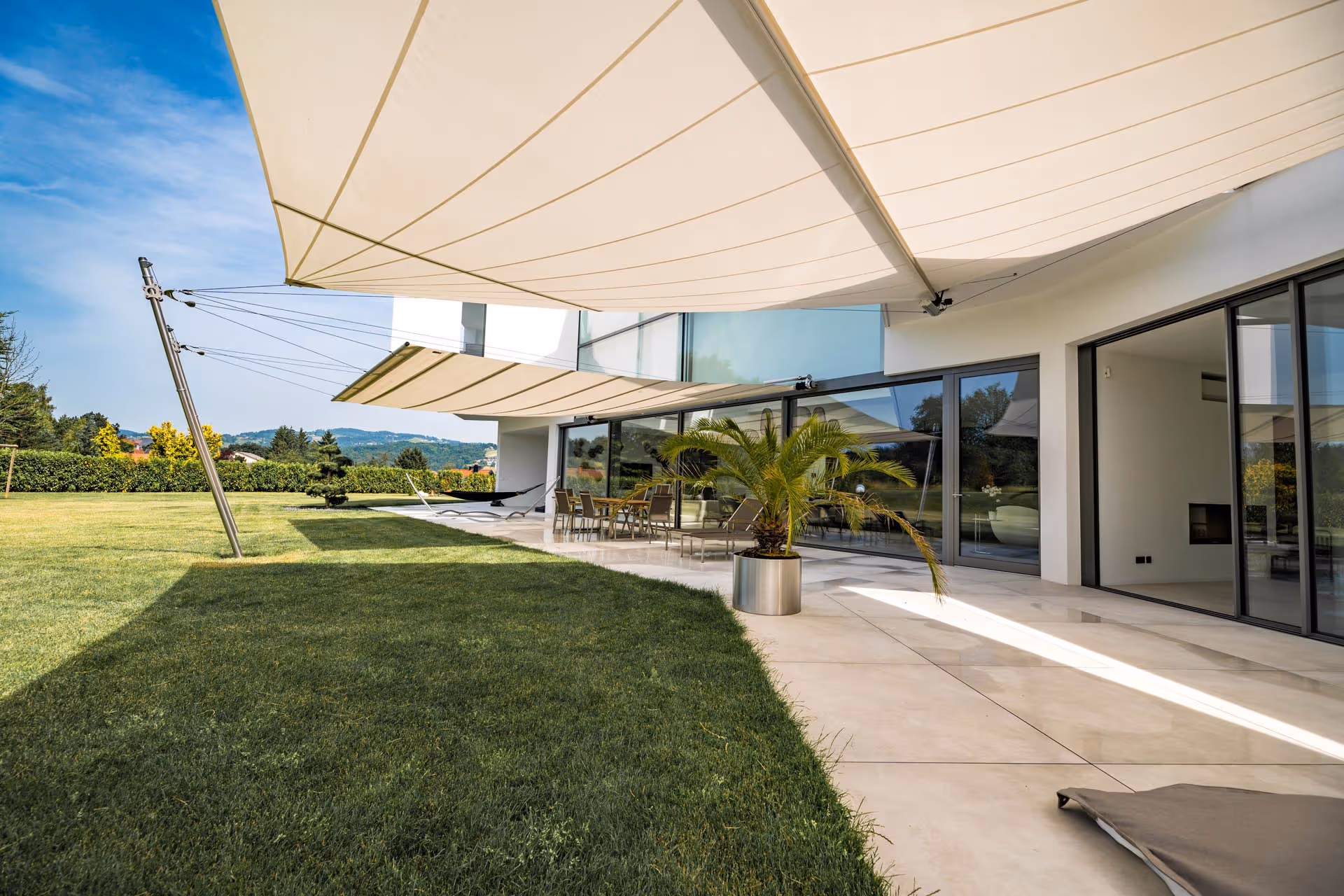 Ein Architektenhaus spiegelt sich im Wasser des Pools, ebenso wie die SunSquare Anlage, die Schatten spendet.