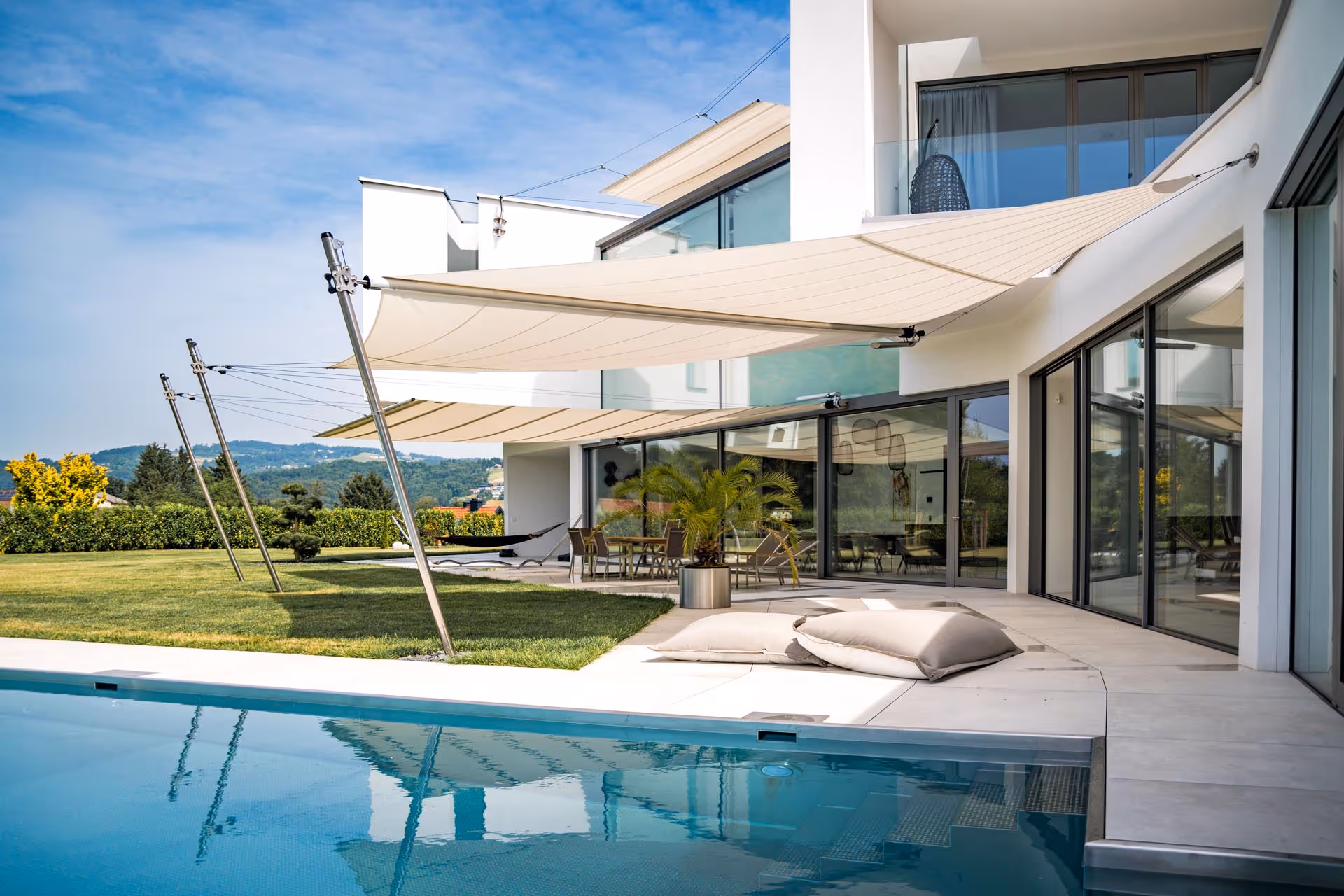 Ein Architektenhaus spiegelt sich im Wasser des Pools, ebenso wie die SunSquare Anlage, die Schatten spendet.