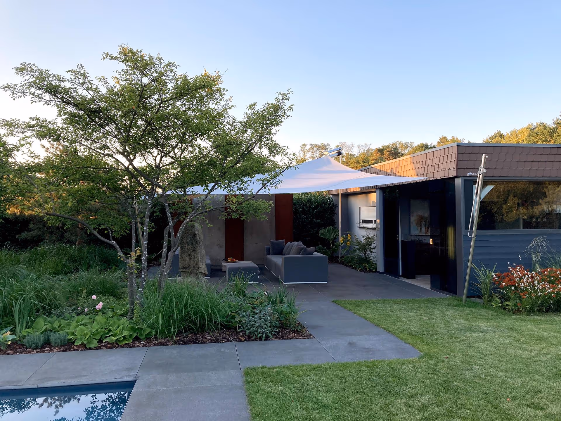 Ein Gartenparadies mit Pool, viel Grün und einem SunSquare Sonnensegel.
