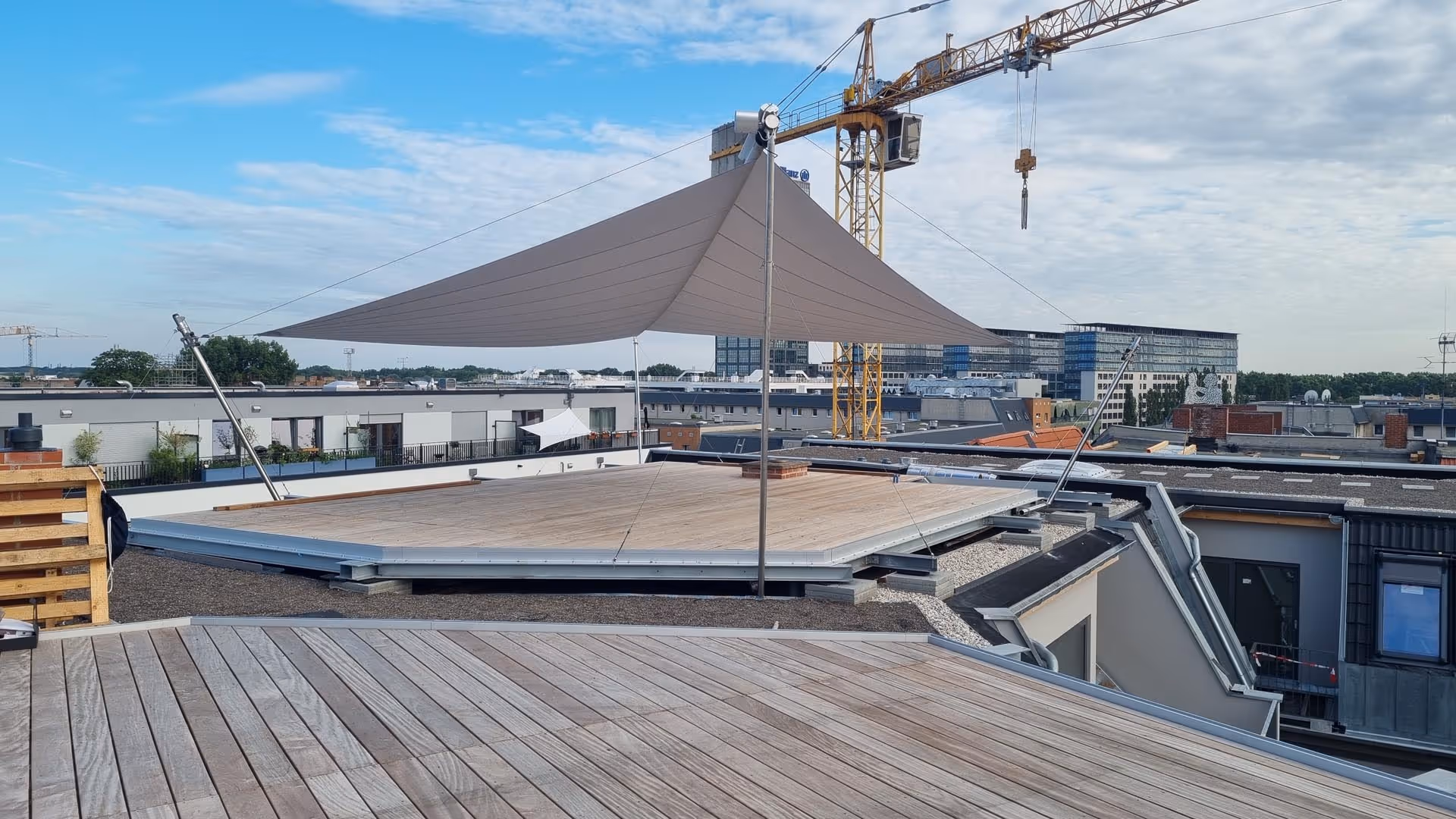 Montagearbeiten: Dachterrasse mit großflächigem SunSquare Sonnensegel in Hellgrau – montiert auf Stahlrahmen mit elektrischen Höhenverstellern über Berlin