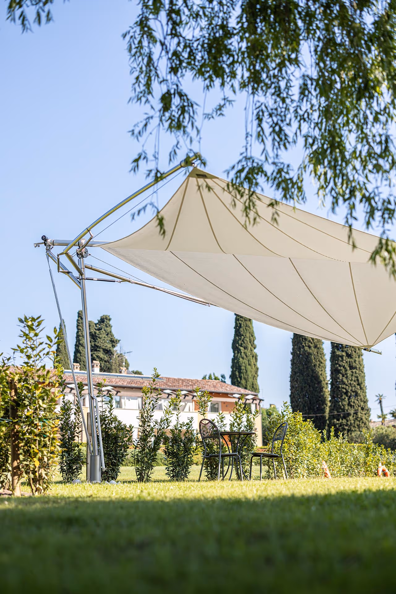 Großzügiger Segelschirm mit Fold & Roll System in einem italienischen Garten – stilvoller Sonnenschutz über Sitzbereich.