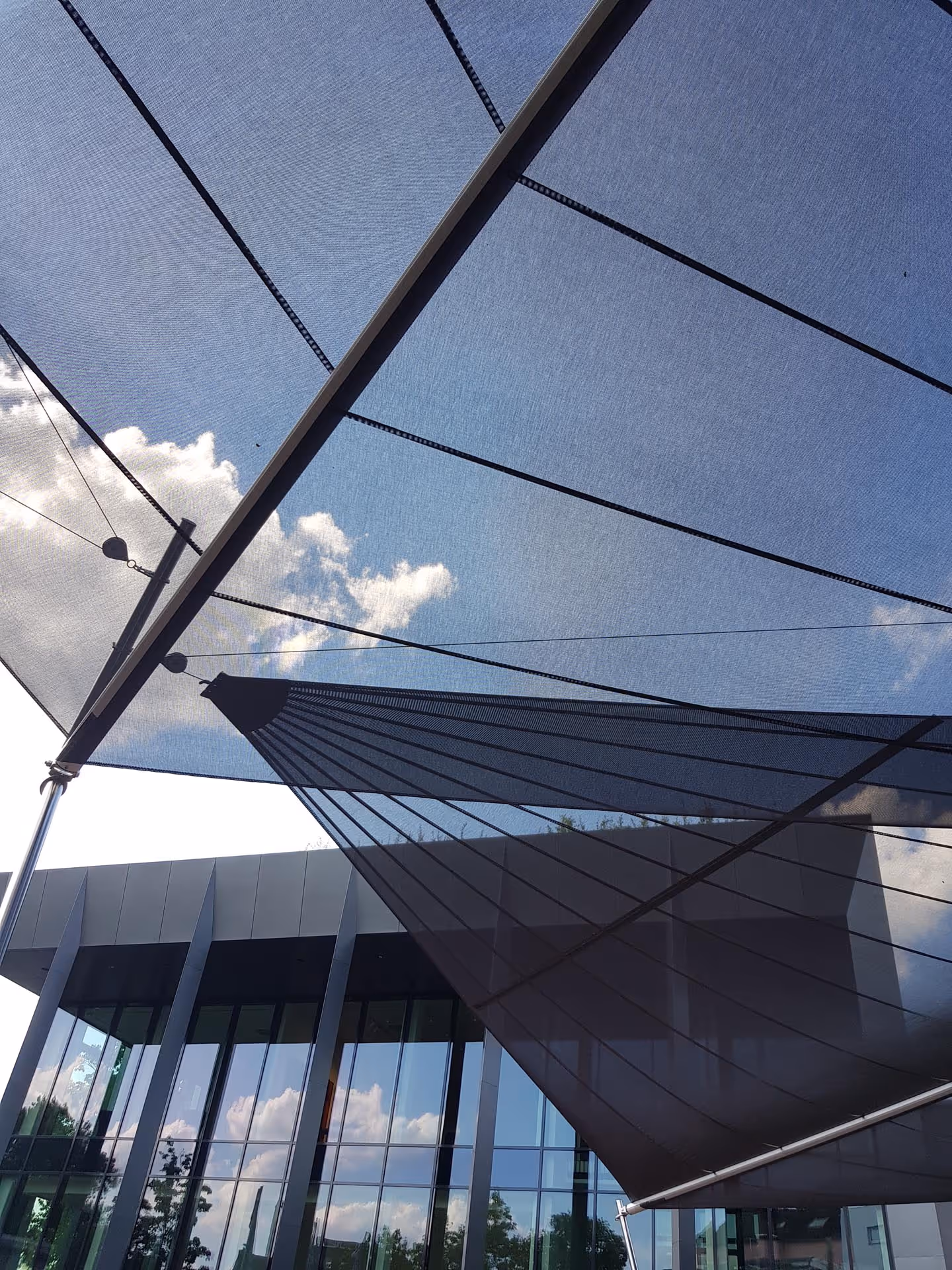 Blick von unten auf die transparenten Segel – lichtdurchlässige Struktur für angenehme Helligkeit und Wetterschutz.