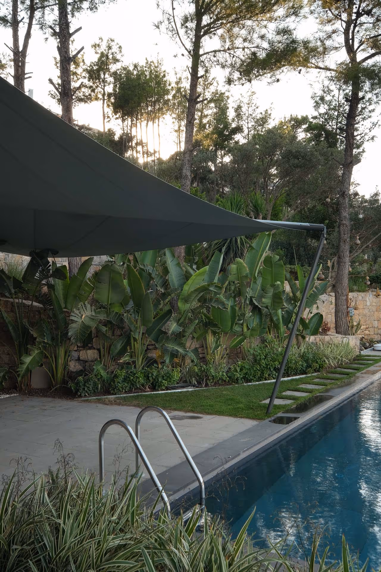 Mystischer, mediterraner Außenberich mit viel Grün und tollem Pool mit Meerblick - um ein SunSquare Segel erweitert.