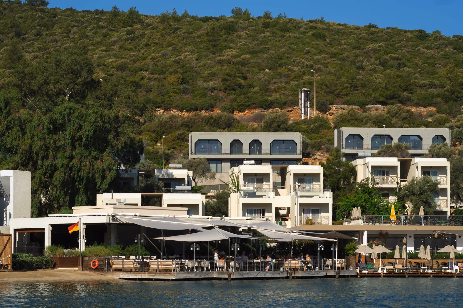 Ein Blick vom Meer auf das Voyage Torba Hotel in Bodrum - man erkennt die SunSquare Segel von der Ferne.