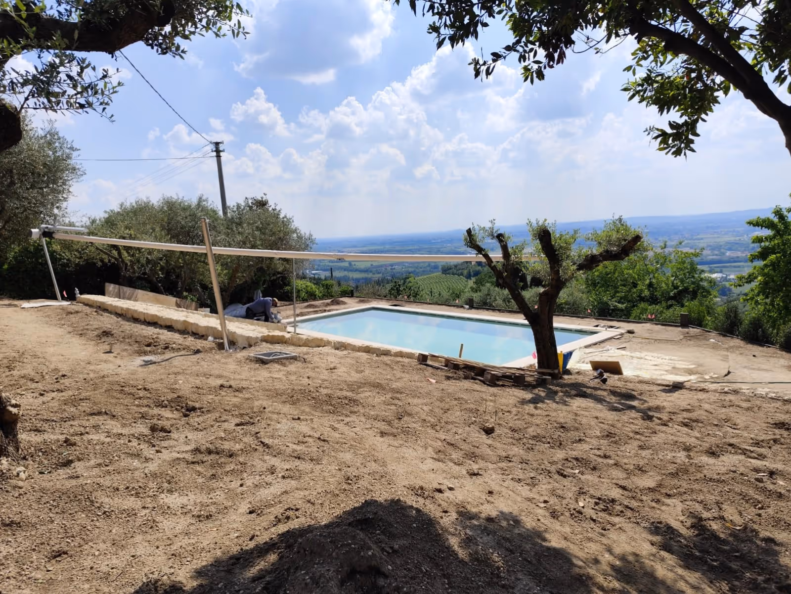 SunSquare® Sonnensegel über mediterranem Poolbereich mit Natursteinmauer und Olivenbäumen in Italien