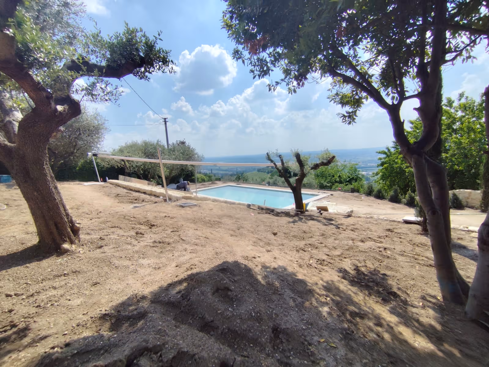 Motorisiertes SunSquare® Sonnensegel in Dickson Infinity Grège über privater Poolanlage in mediterraner Landschaft