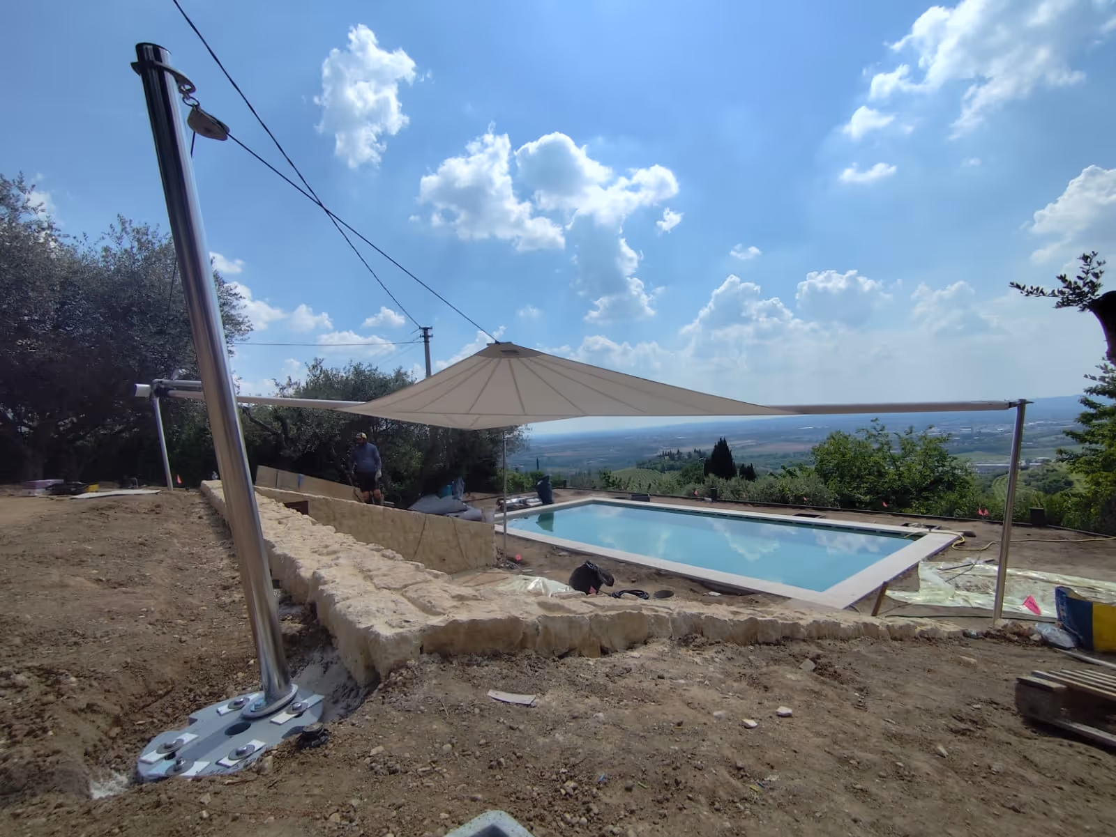 SunSquare® Sonnenschutzlösung in trapezförmiger Ausführung über Pool, eingebettet in mediterrane Umgebung