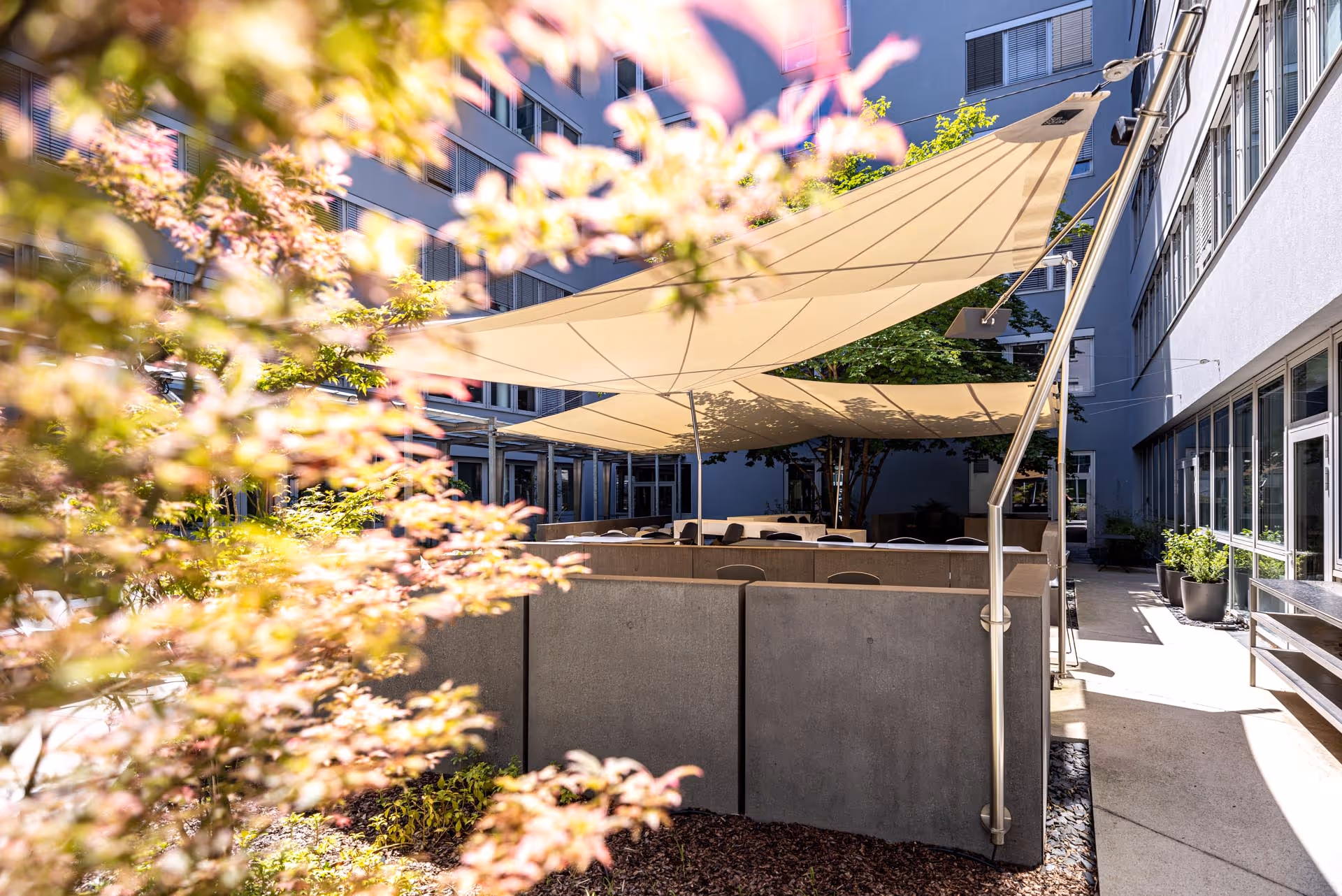 Sonnengeschützter Pausenbereich mit SunSquare® Segelanlagen – Innenhofgestaltung mit M&G Innenarchitektur