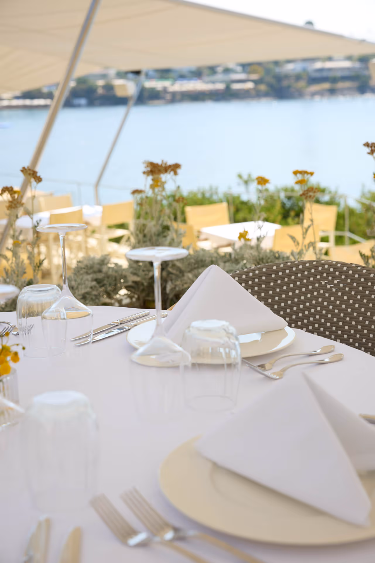 Ein schön gedeckter Tisch, geschützt durch SunSquare Sonnensegel im Hintergrund das weiter Meer. Ein Traum von einem Restaurant an der Küste.