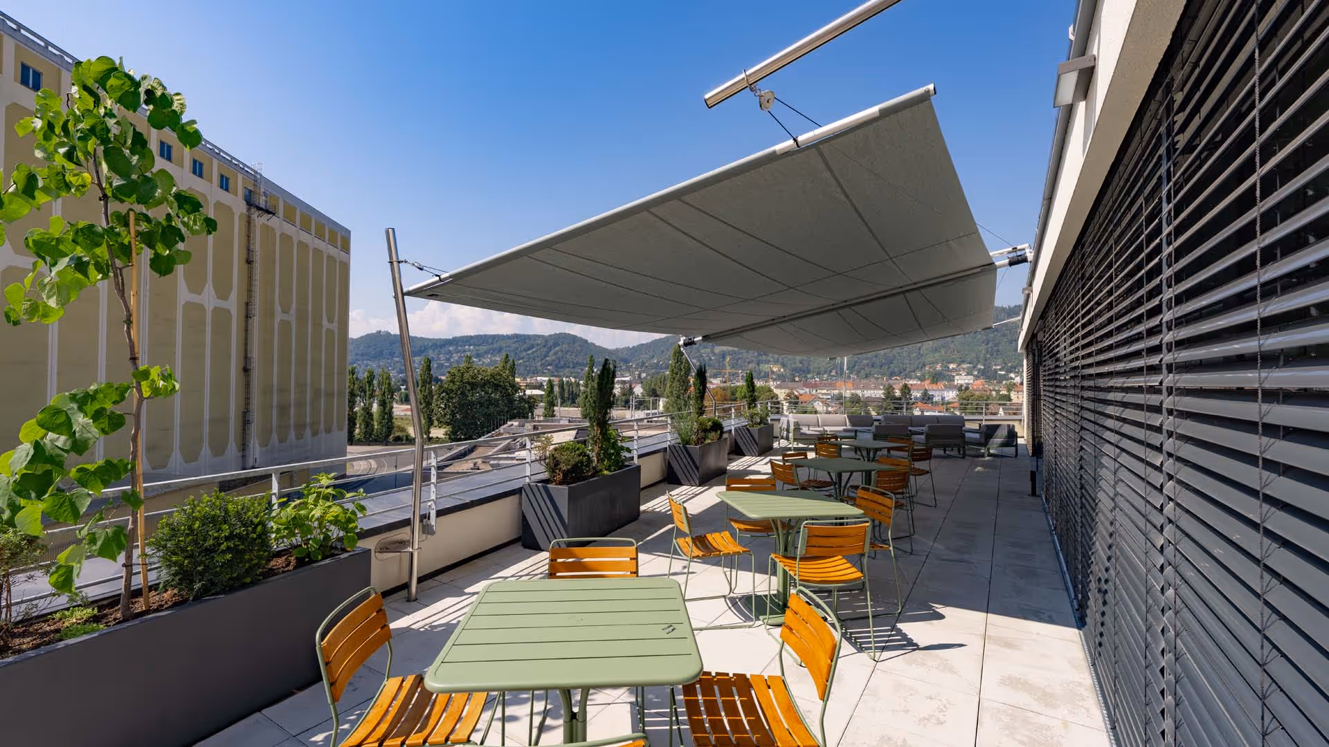 Zwei SunSquare Rechtecksegel mit 57 m² und 58 m² Fläche – stilvoller Sonnen- und Regenschutz auf einer exponierten Dachterrasse für Mitarbeitende und Besucher:innen.
