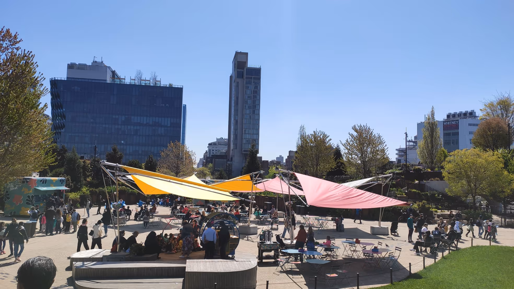 Crowd relaxing under the FOLD & ROLL parasol from SunSquare in Little Island Park, New York.