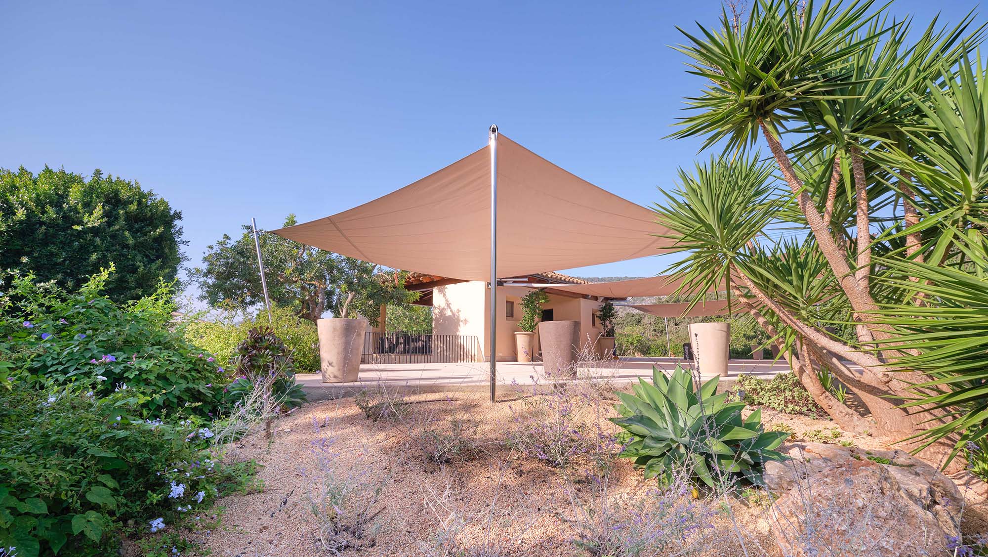 A green, tropical garden in Spain, the spacious terrace area is spanned by three SunSquare awnings.