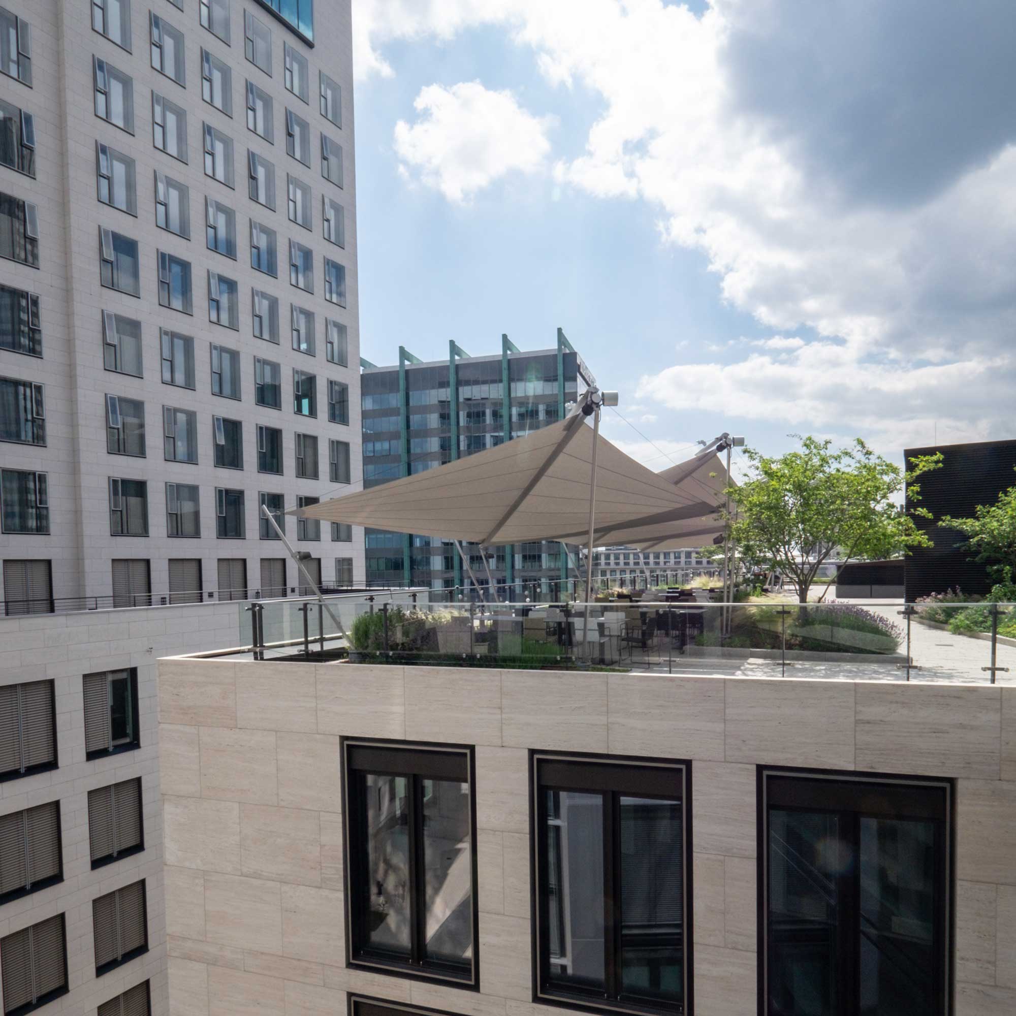 Großzügige Büroterrasse mit fünf SunSquare Strahlensegeln für entspannte Pausen im Freien.