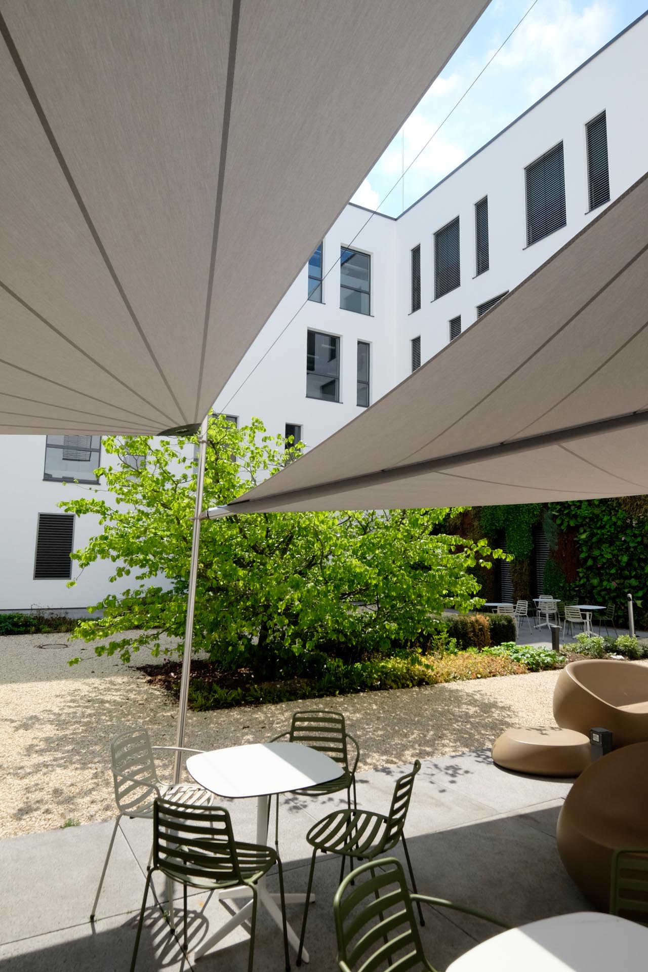 Drei gekoppelte SunSquare Sonnensegel über der Mitarbeiterterrasse von ENNI